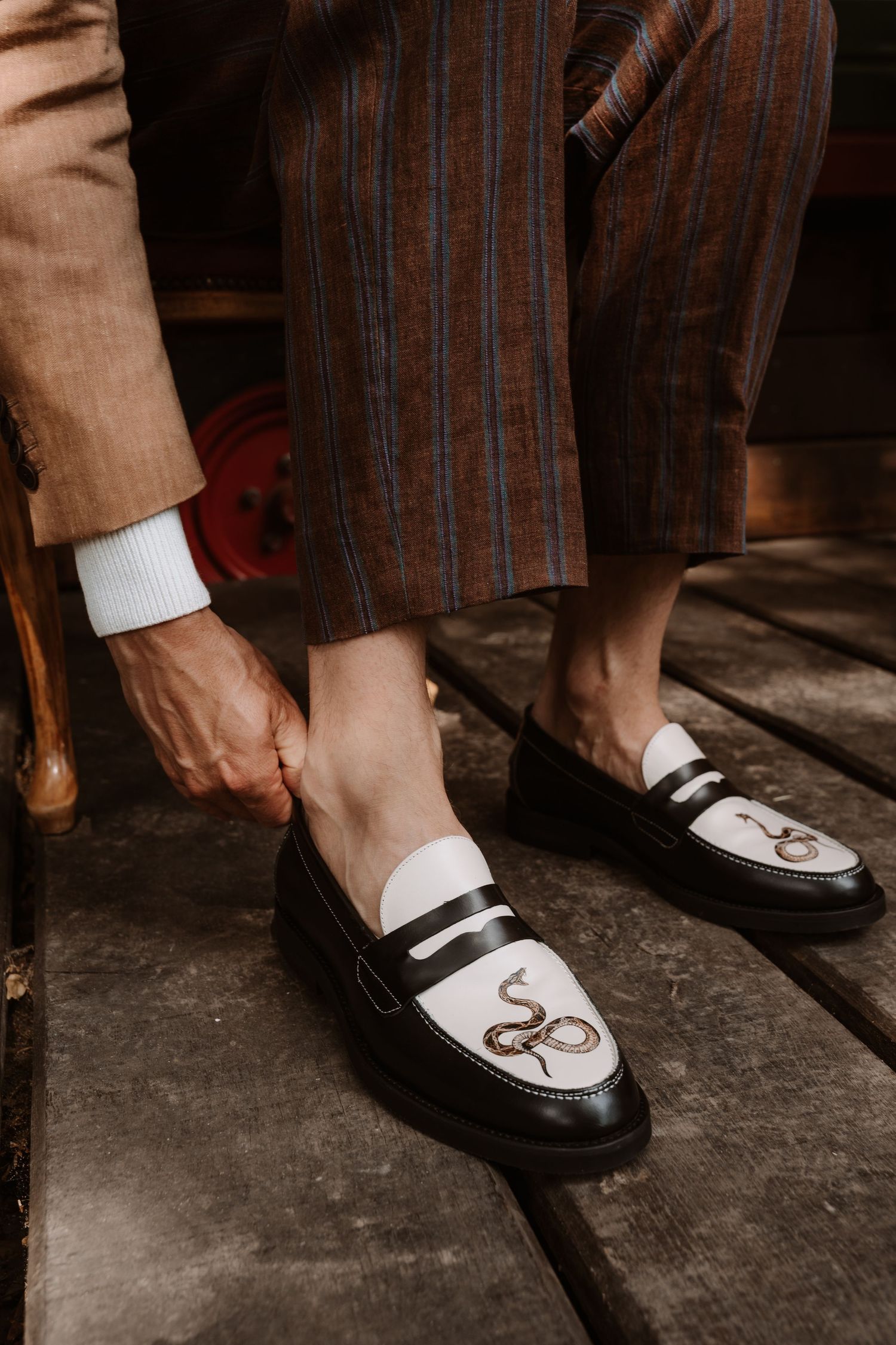 Close-up of vintage two-tone loafers with decorative stitching on a wooden floor.
