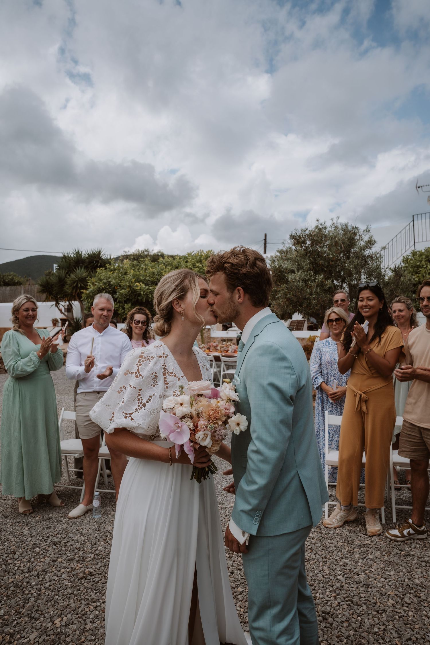 Wedding celebration with guests in mint green and earth tone attire gathered outdoors.