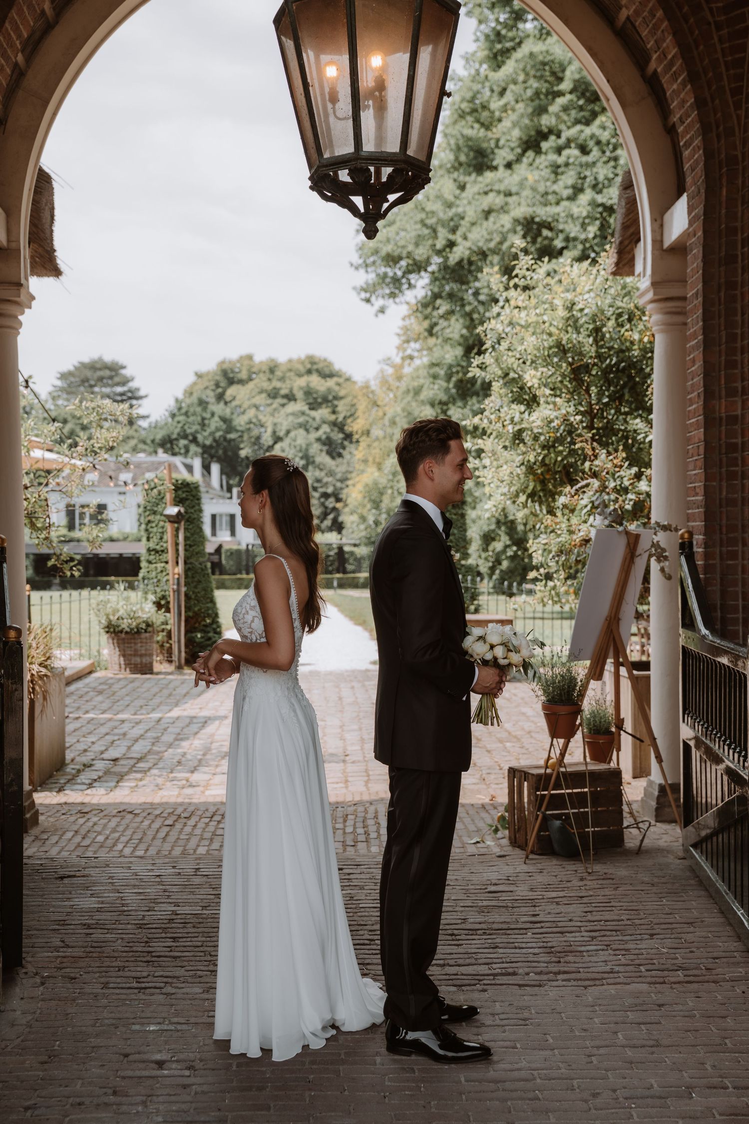 Wedding couple standing under a brick archway during their first look moment.
