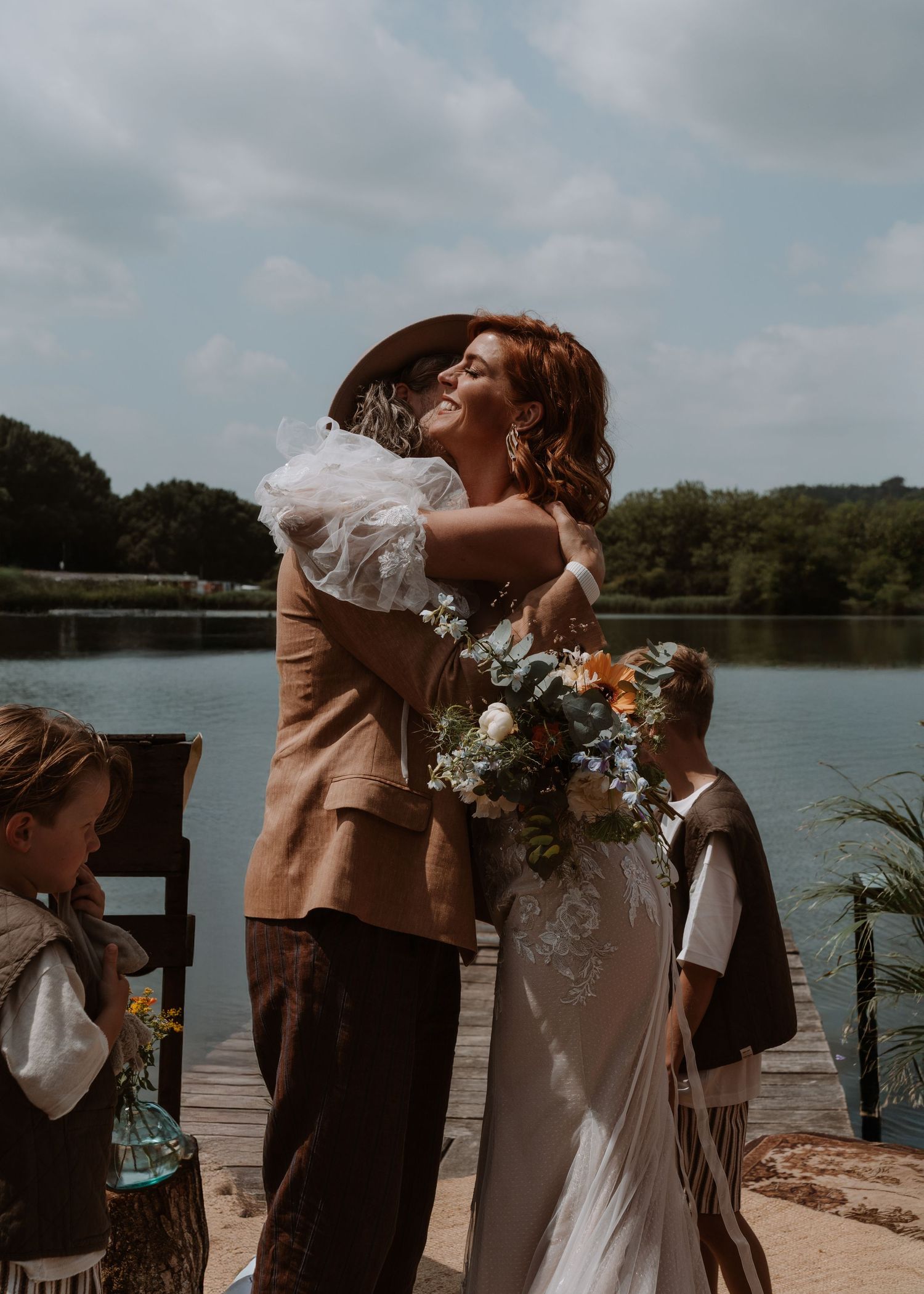 A romantic outdoor wedding ceremony by a lake with floral decorations and warm earth tones.