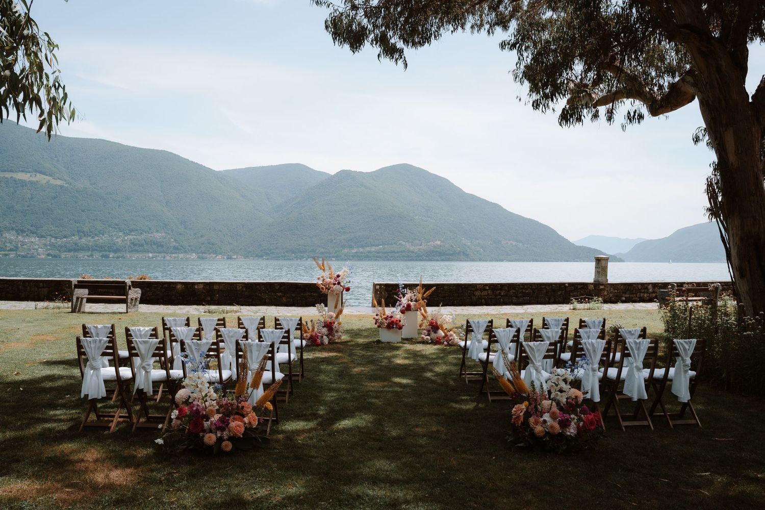 Panoramic sequence of wedding guests seated in chairs overlooking a serene mountain lake during an outdoor ceremony.