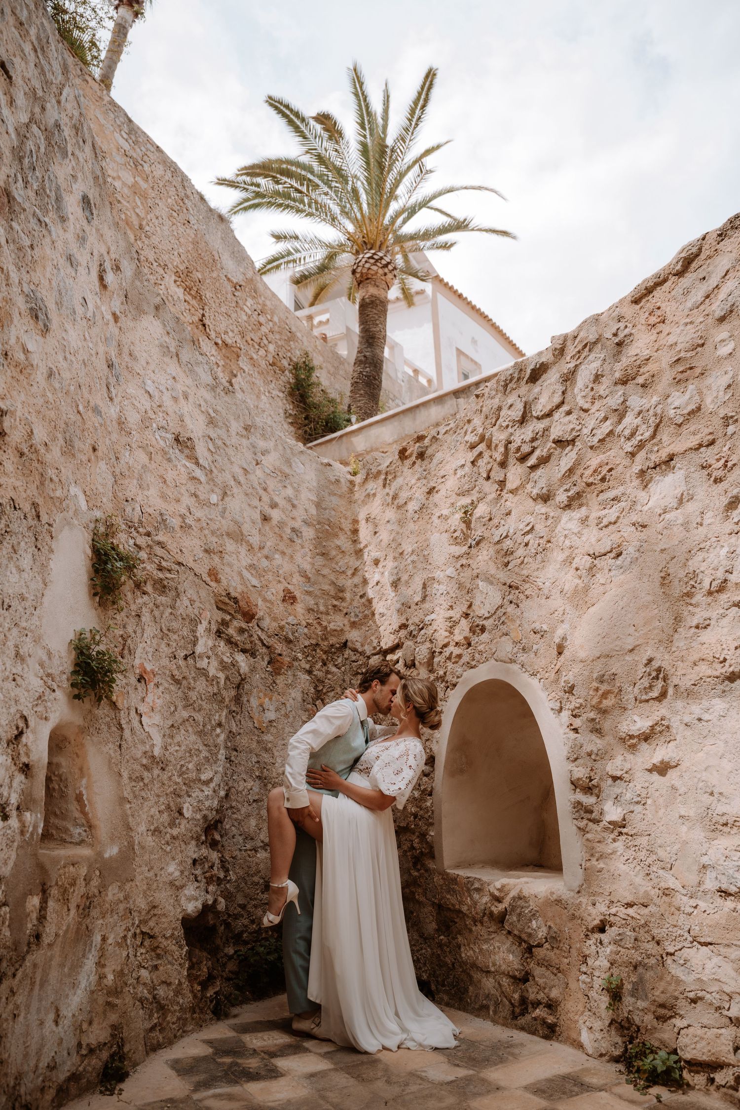 Wedding photography session in historic stone courtyard with palm trees.