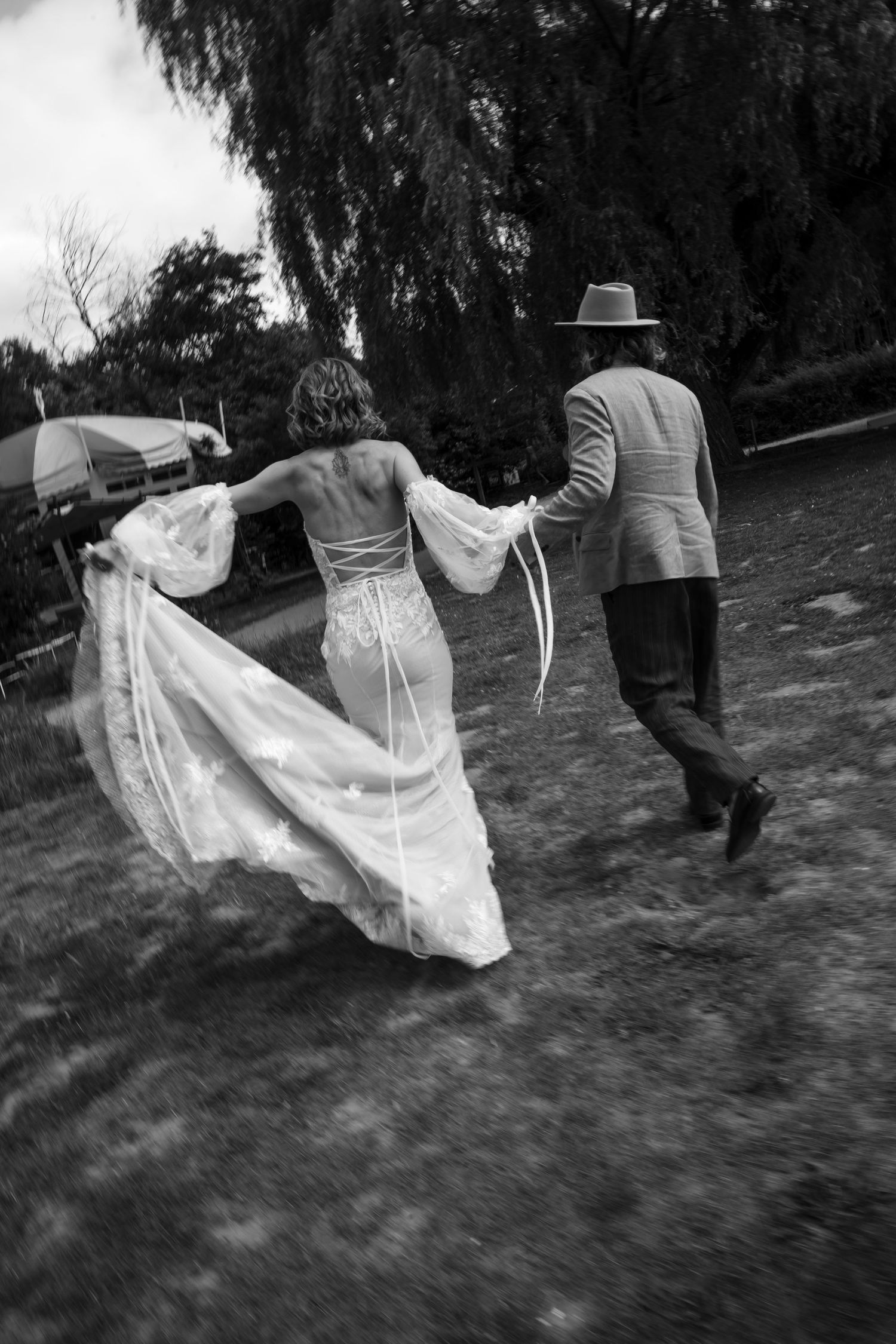 A sequence of black and white photos showing a flowing wedding dress moving gracefully across a grassy field.