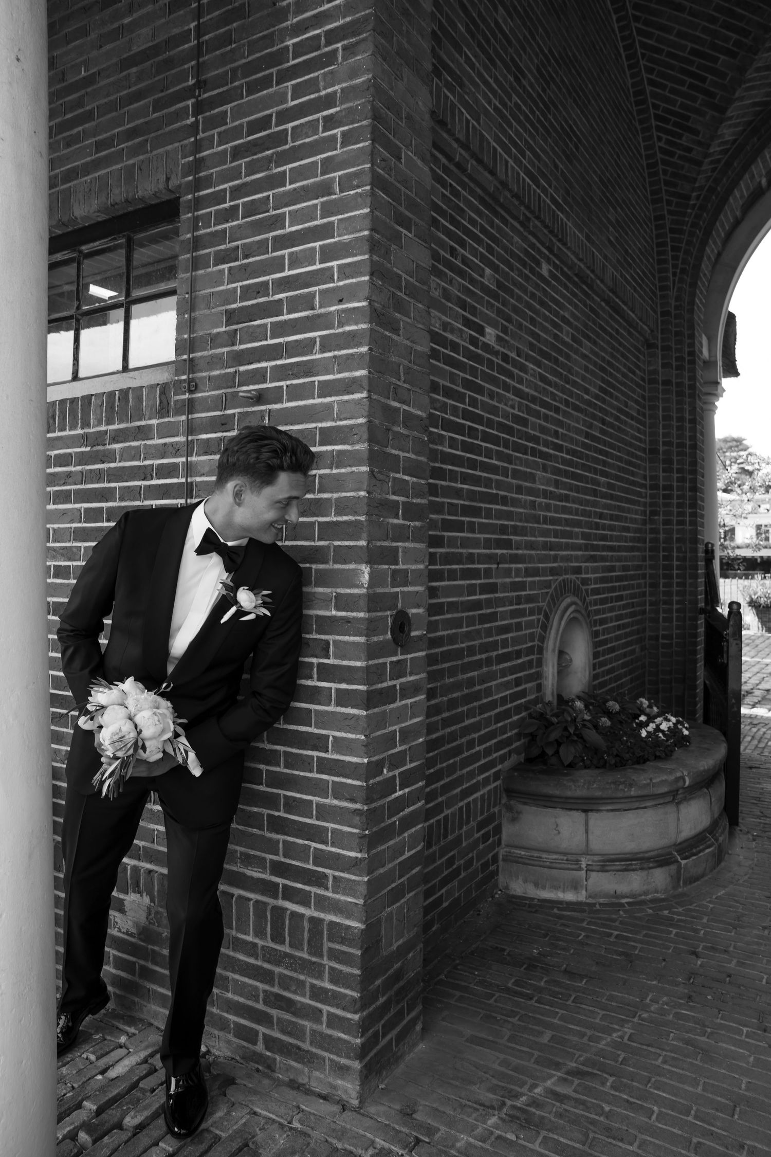 Formal wedding party lined up along a brick colonnade with white columns.