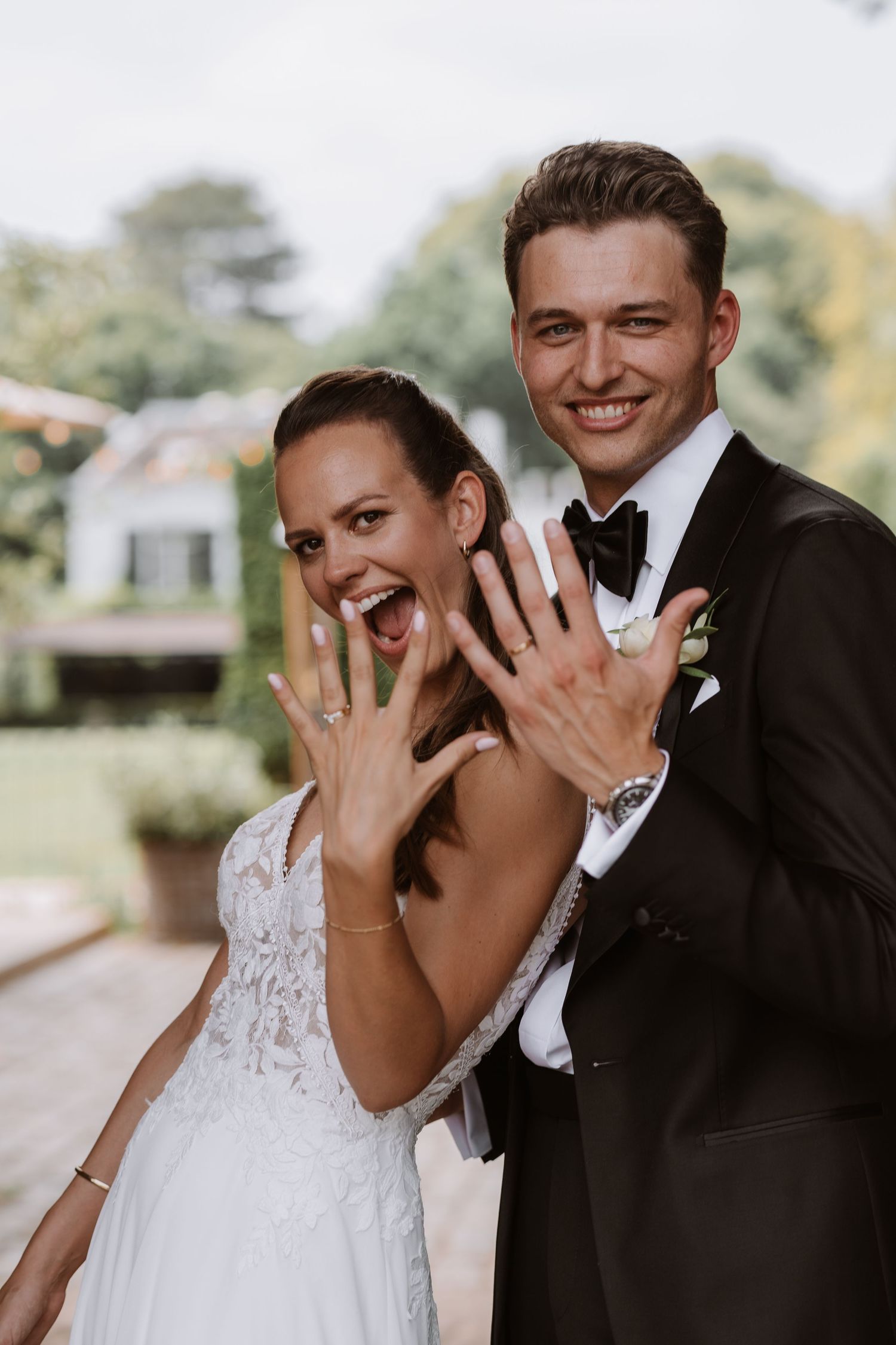 Happy newlyweds showing off their wedding rings with joyful expressions.