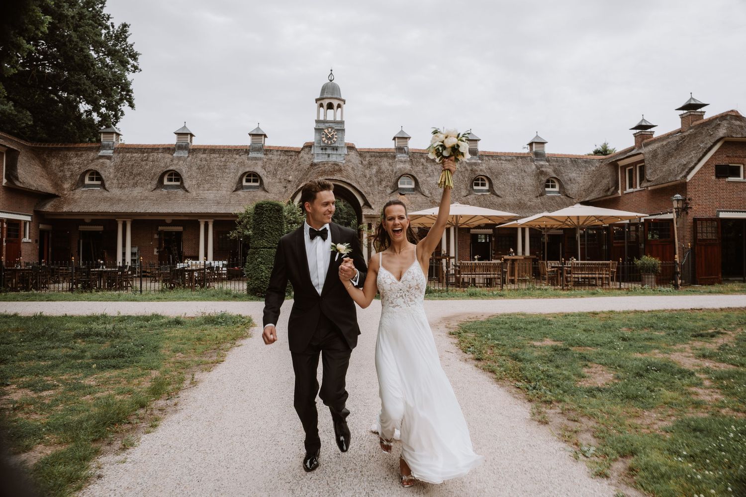 Wedding couple walking along a path towards historic stable buildings on their special day.