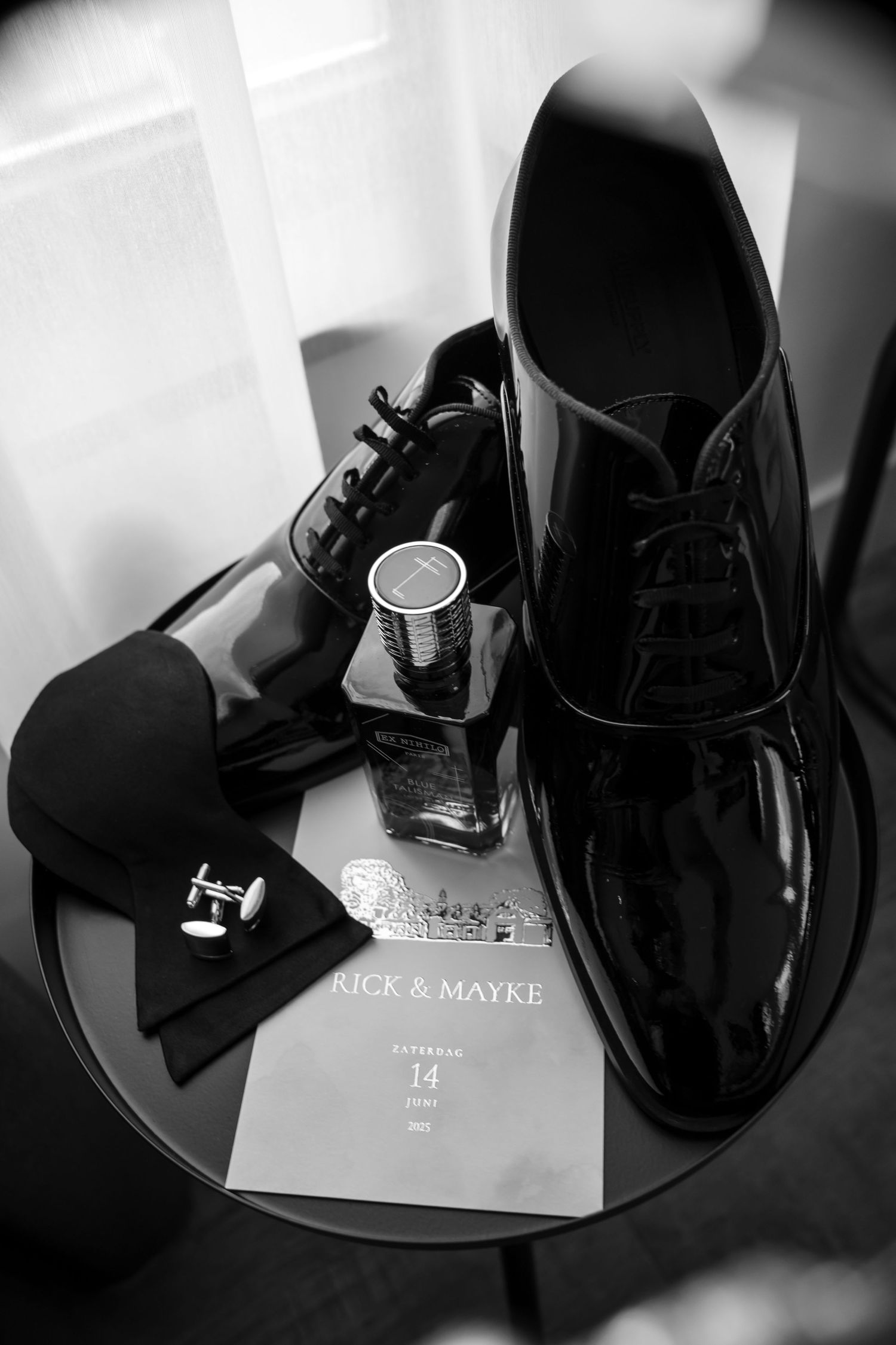 Black and white detail shot of formal shoes and wedding stationery.