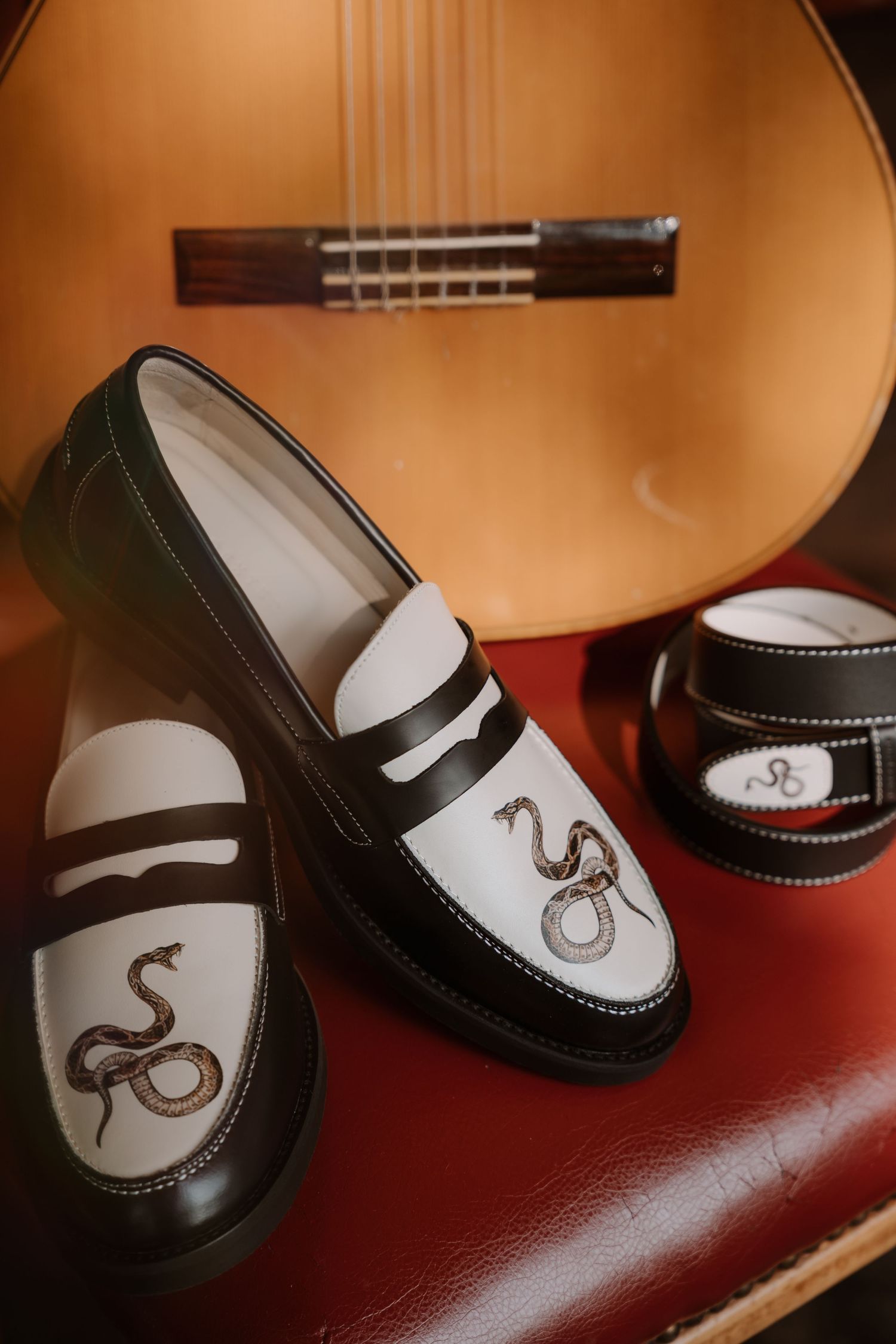Stylish black and white leather shoes with octopus design detail on red surface.