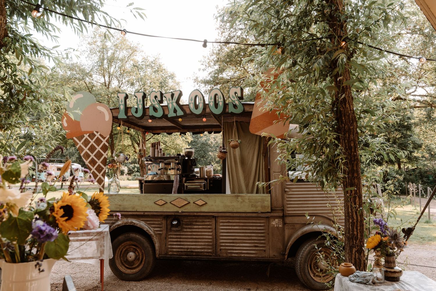 A rustic outdoor wedding venue with vintage trucks and natural woodland scenery.