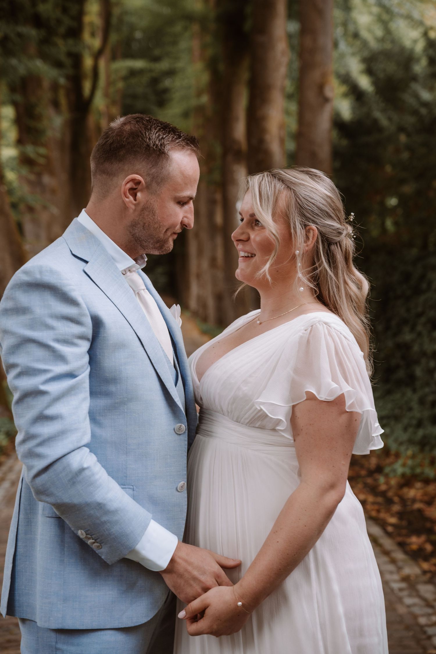 A romantic wedding couple shares intimate moments in a wooded setting.