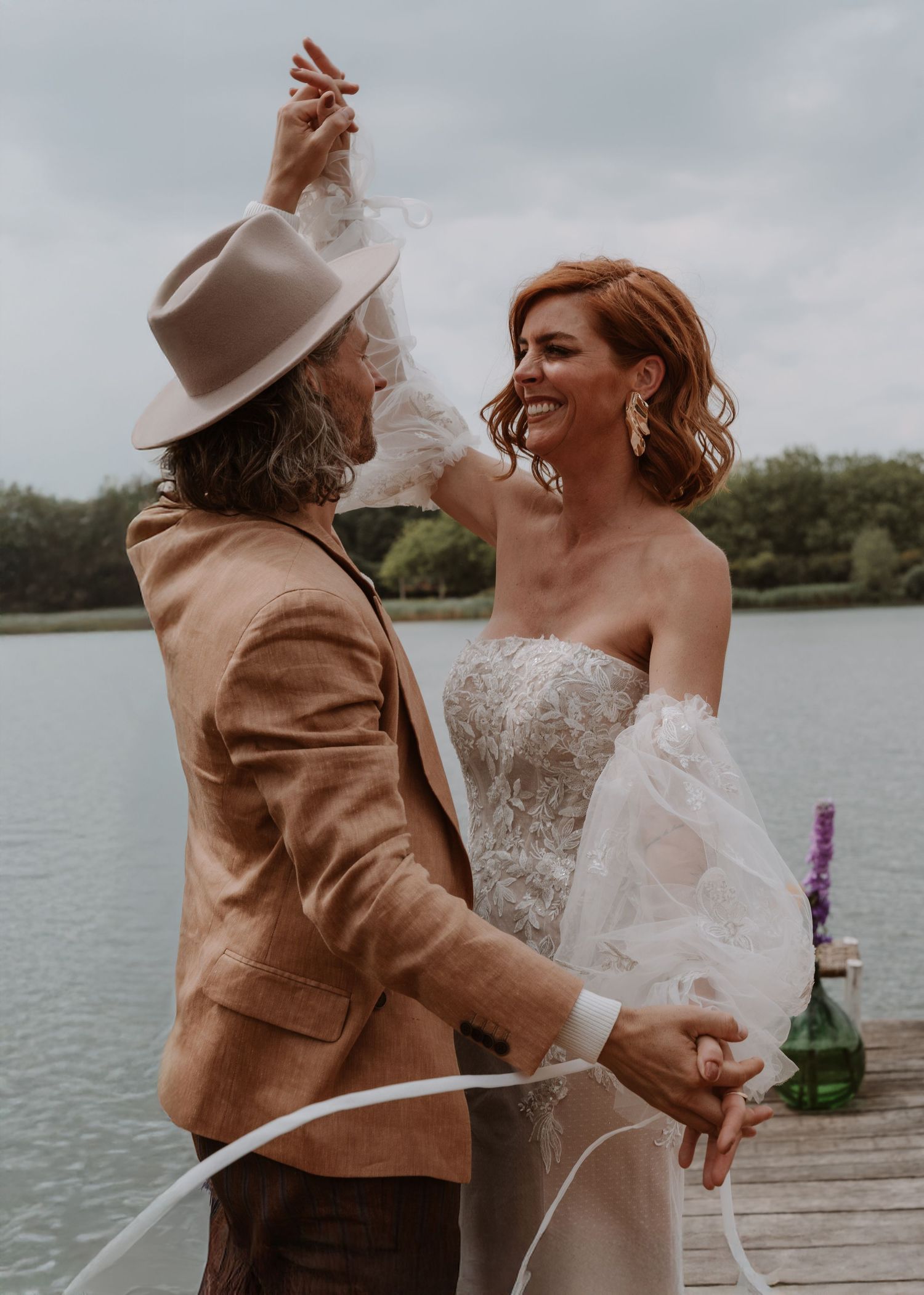 A romantic moment between newlyweds on a lakeside dock during their wedding ceremony.
