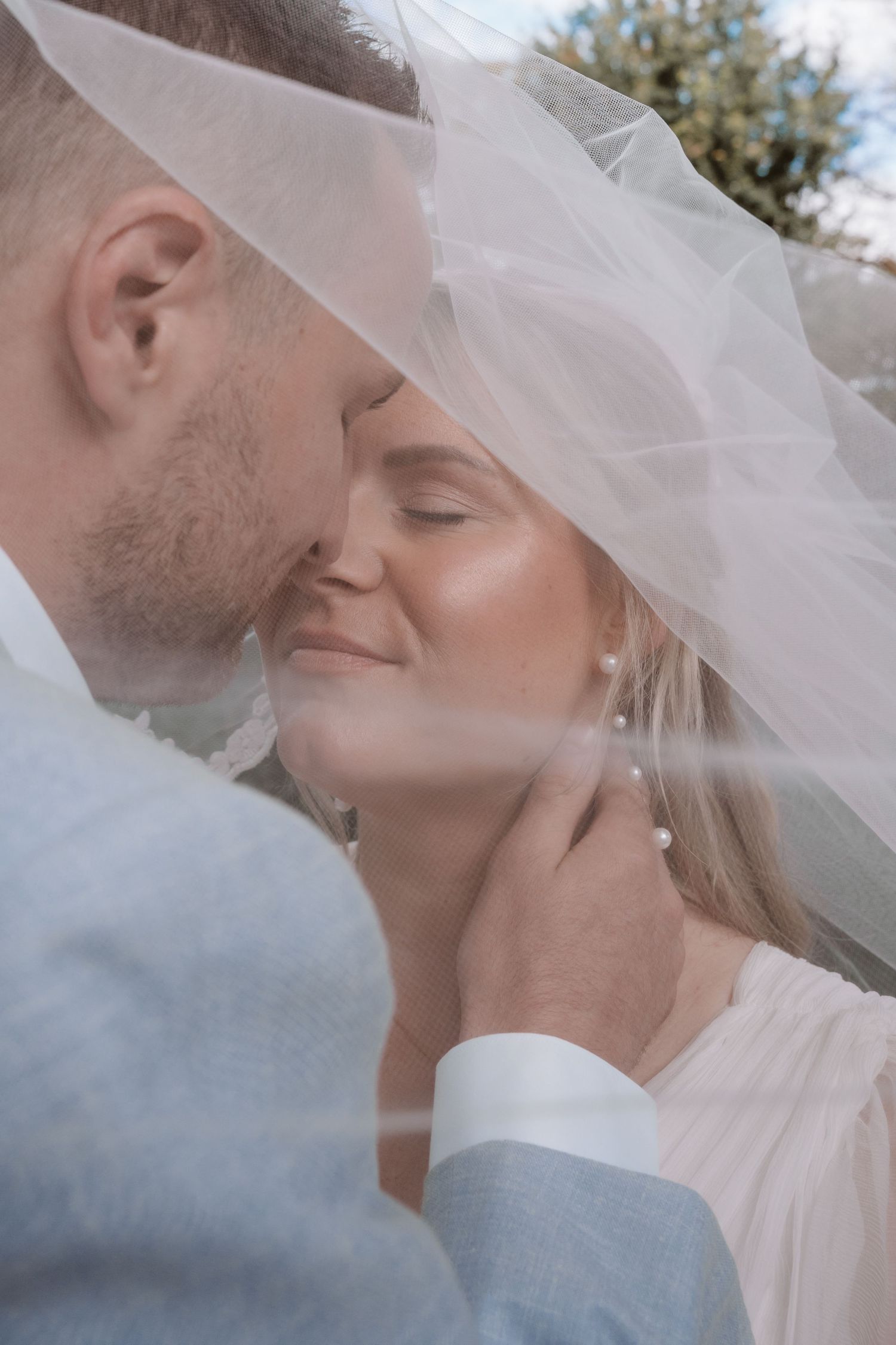 An intimate wedding portrait through a delicate white veil.