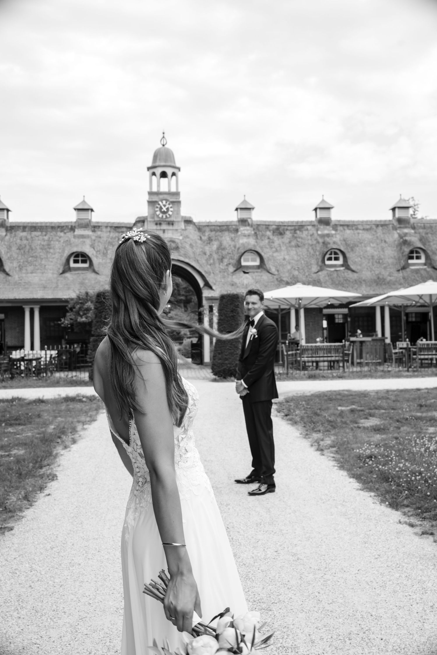 Black and white photo of a wedding couple on the grounds of a historic stable building.