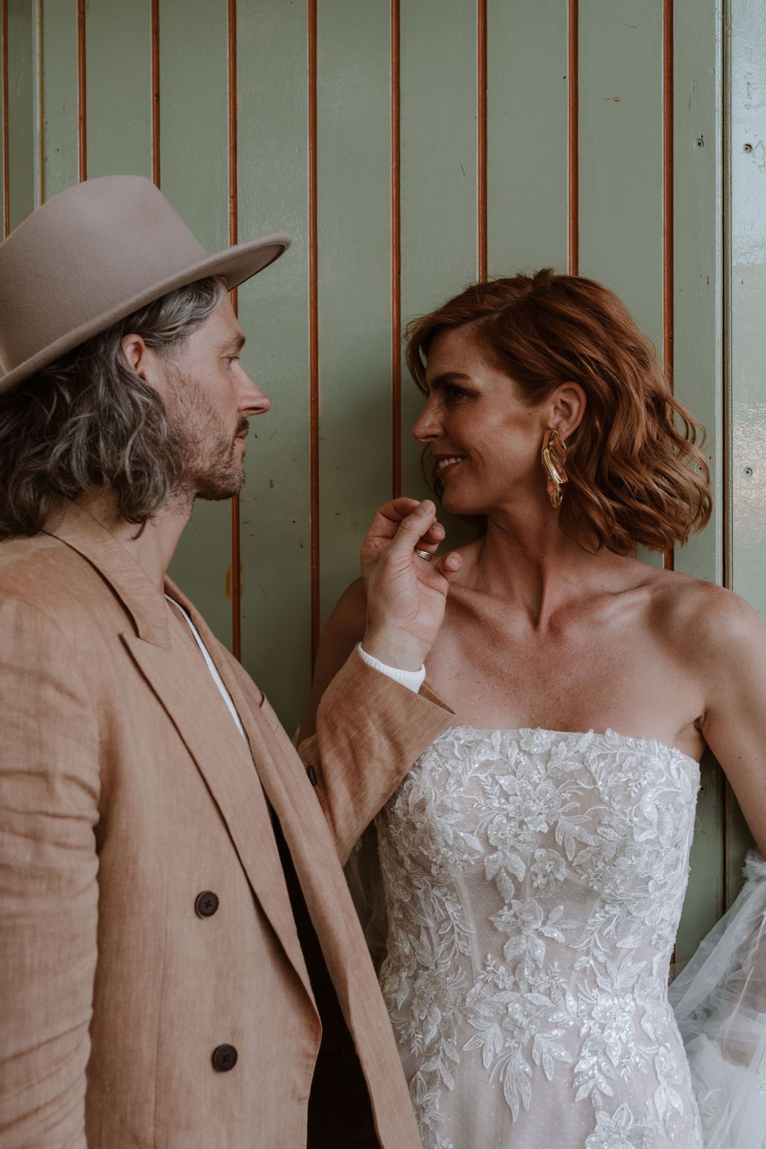 A couple shares tender moments against a striped wall backdrop in a series of candid wedding photos.