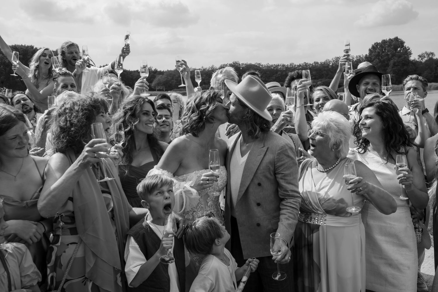 Black and white photo of wedding celebration with guests cheering outdoors.