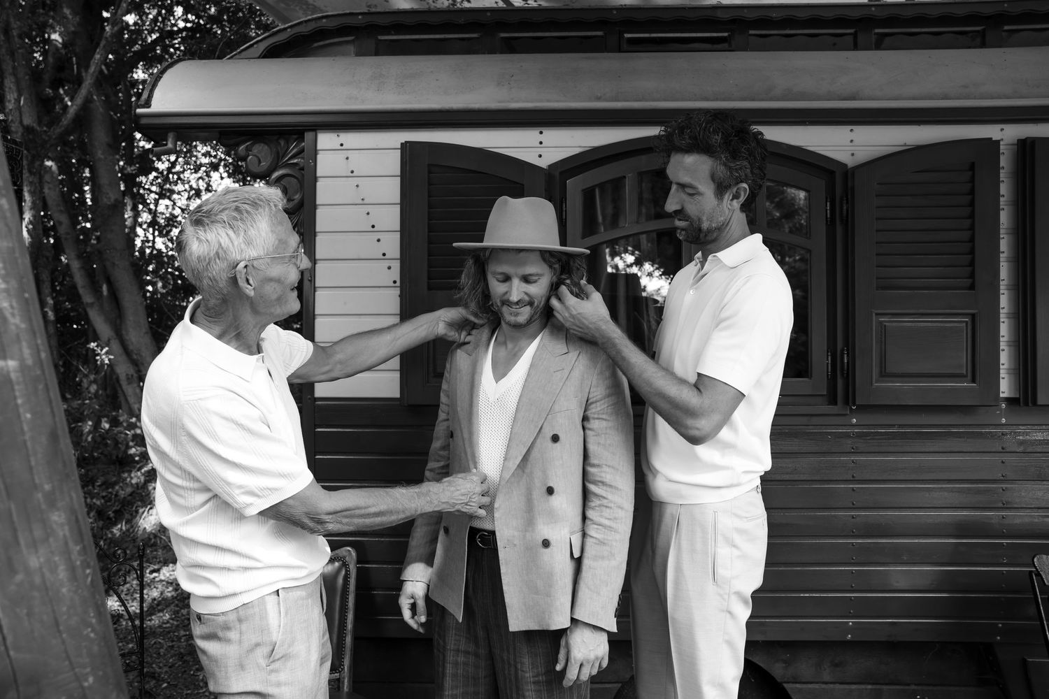 People in white shirts and formal wear greeting each other outside vintage house.