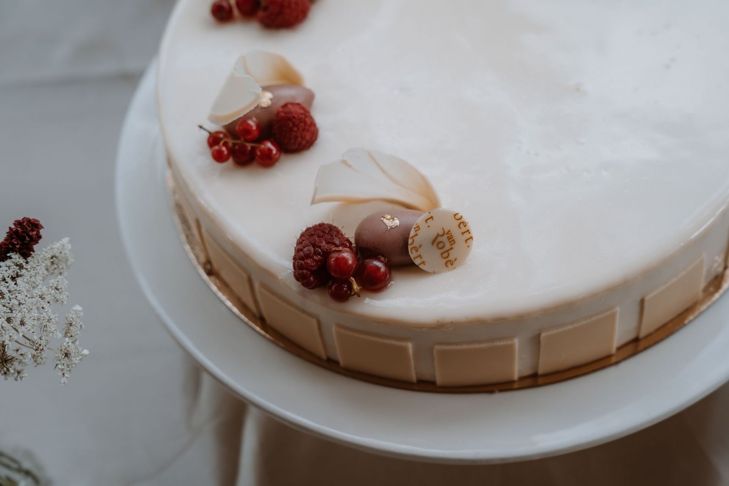Elegant white wedding cake decorated with fresh red berries and chocolate accents.