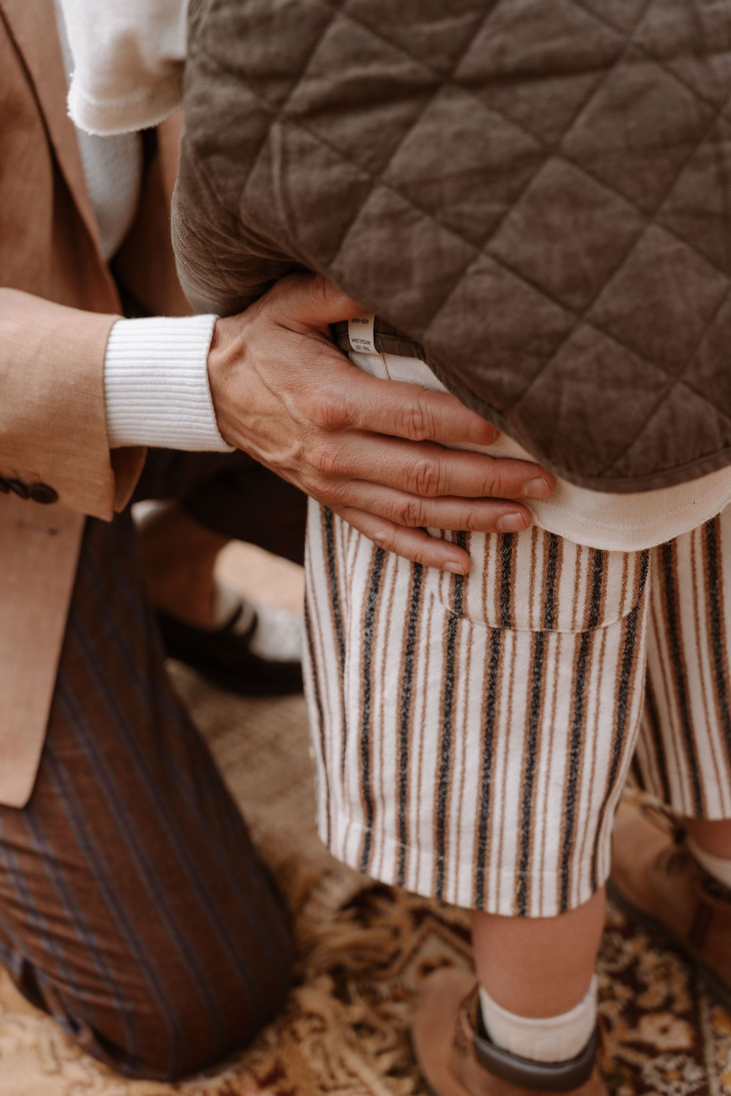 Close-up of hands touching a striped fabric, showing intimate wedding day details.