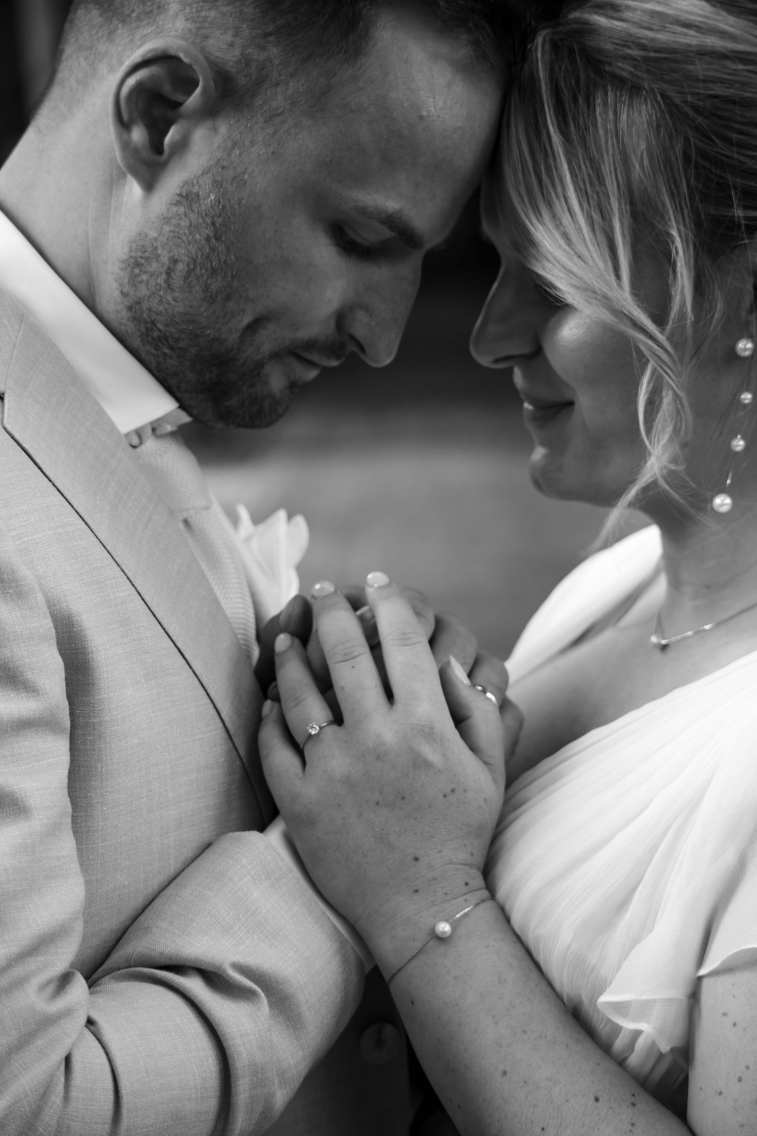 An intimate black and white portrait of a couple holding hands during their wedding.
