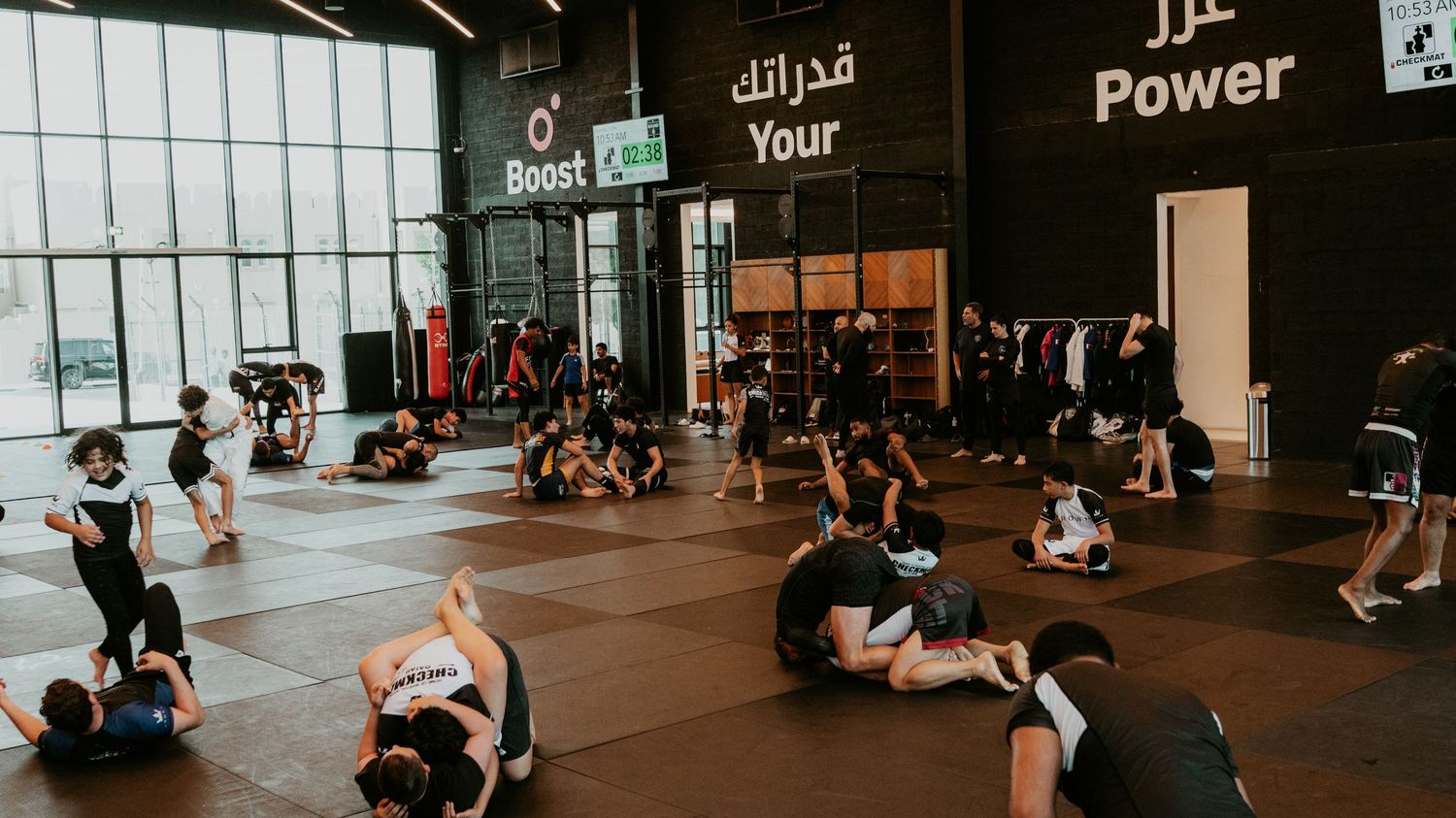 Wide-angle view of athletes training on the mat during a large group martial arts class