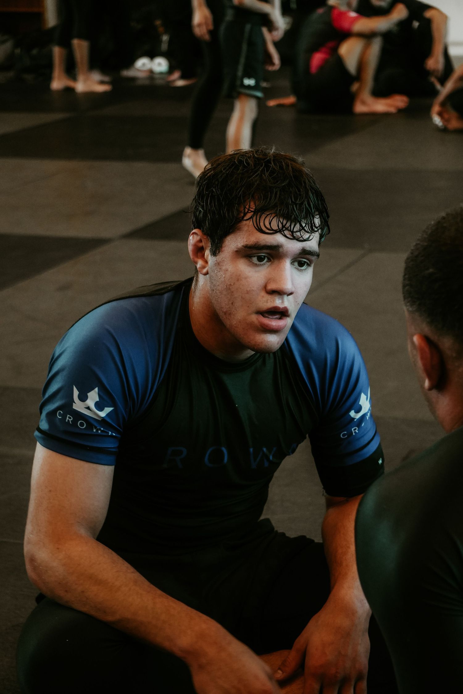 Portrait of a male BJJ fighter in a blue shirt looking focused and intense during training