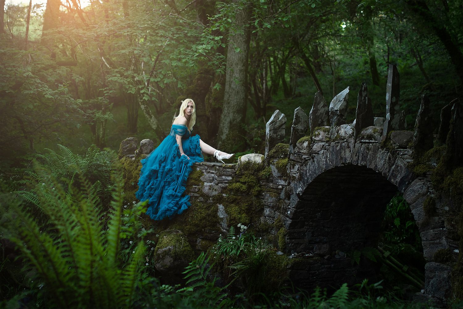 Sagolikt porträtt av vacker blond kvinna i mystisk skog vid Fairy Bridge i Skottland fotograferad av fotograf utanför Göteborg.
