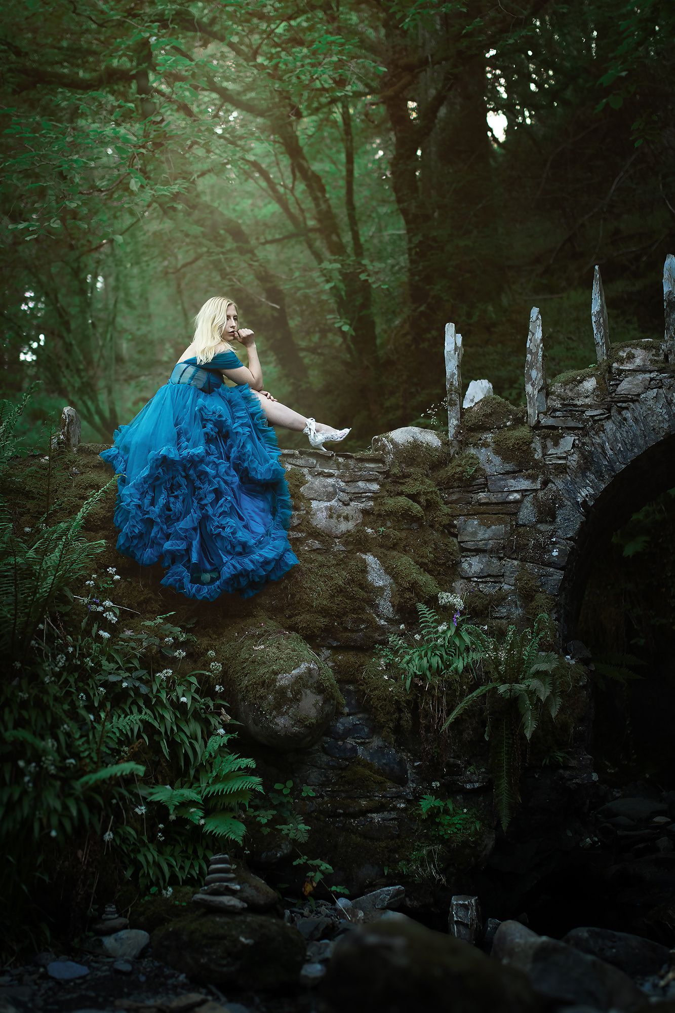 Sagolikt porträtt av vacker blond kvinna i mystisk skog vid Fairy Bridge i Skottland fotograferad av fotograf utanför Göteborg.