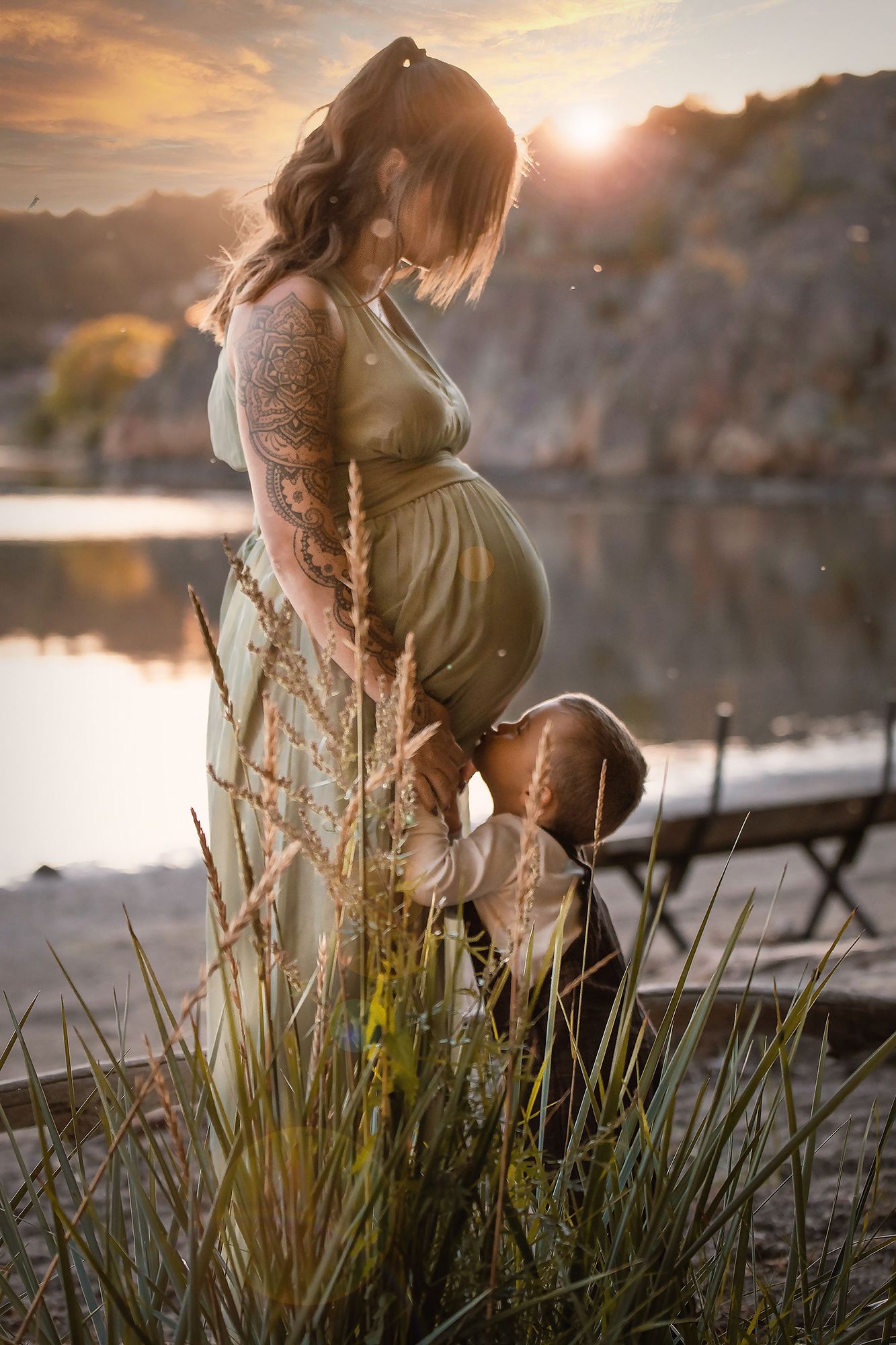 Sagolik fotografering på gravid kvinna och barn vid strandkanten i Munkedal, mjukt naturligt ljus i solnedgång utanför Göteborg.