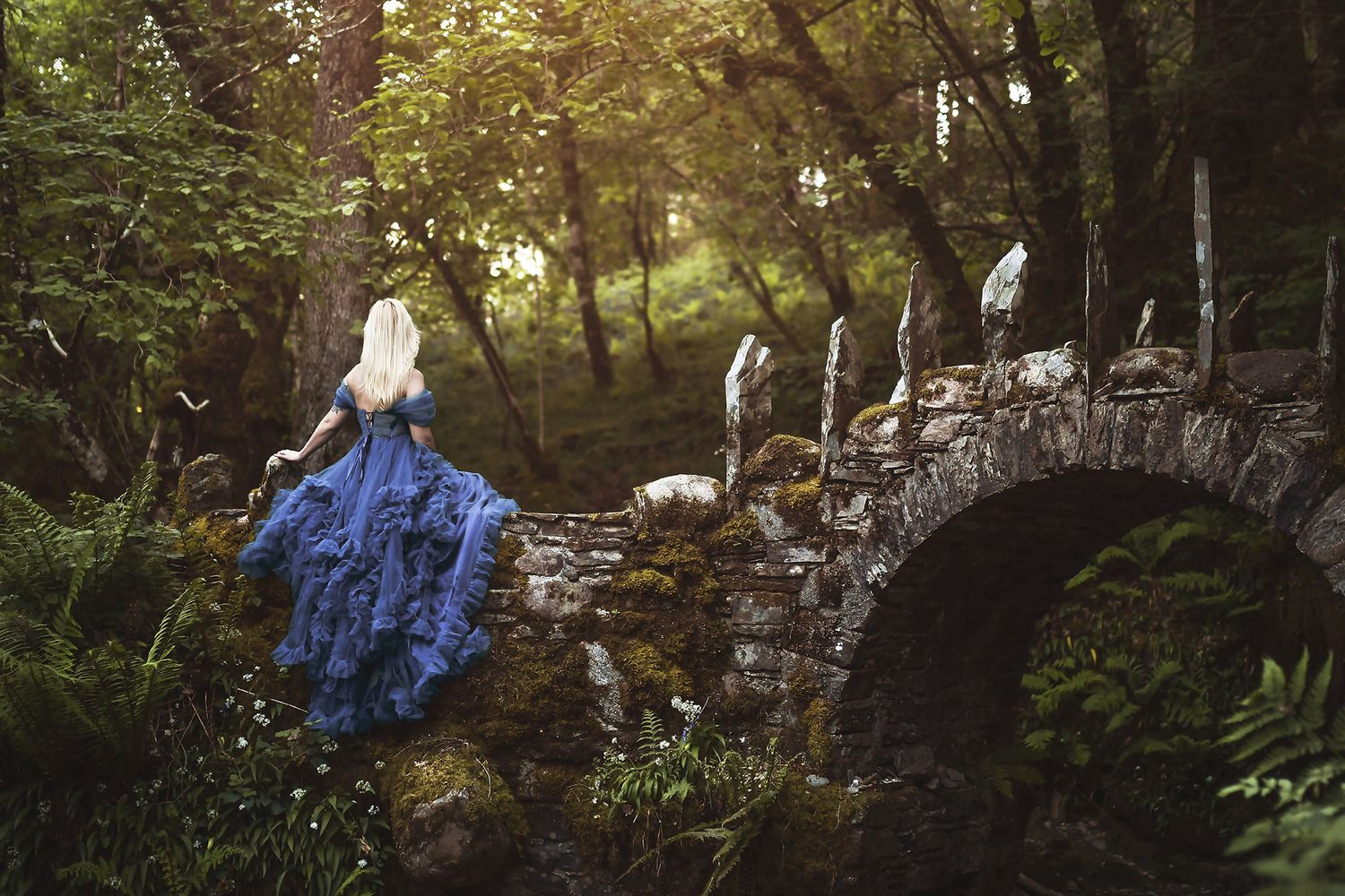 Sagolikt porträtt av vacker blond kvinna i mystisk skog vid Fairy Bridge i Skottland fotograferad av fotograf utanför Göteborg.