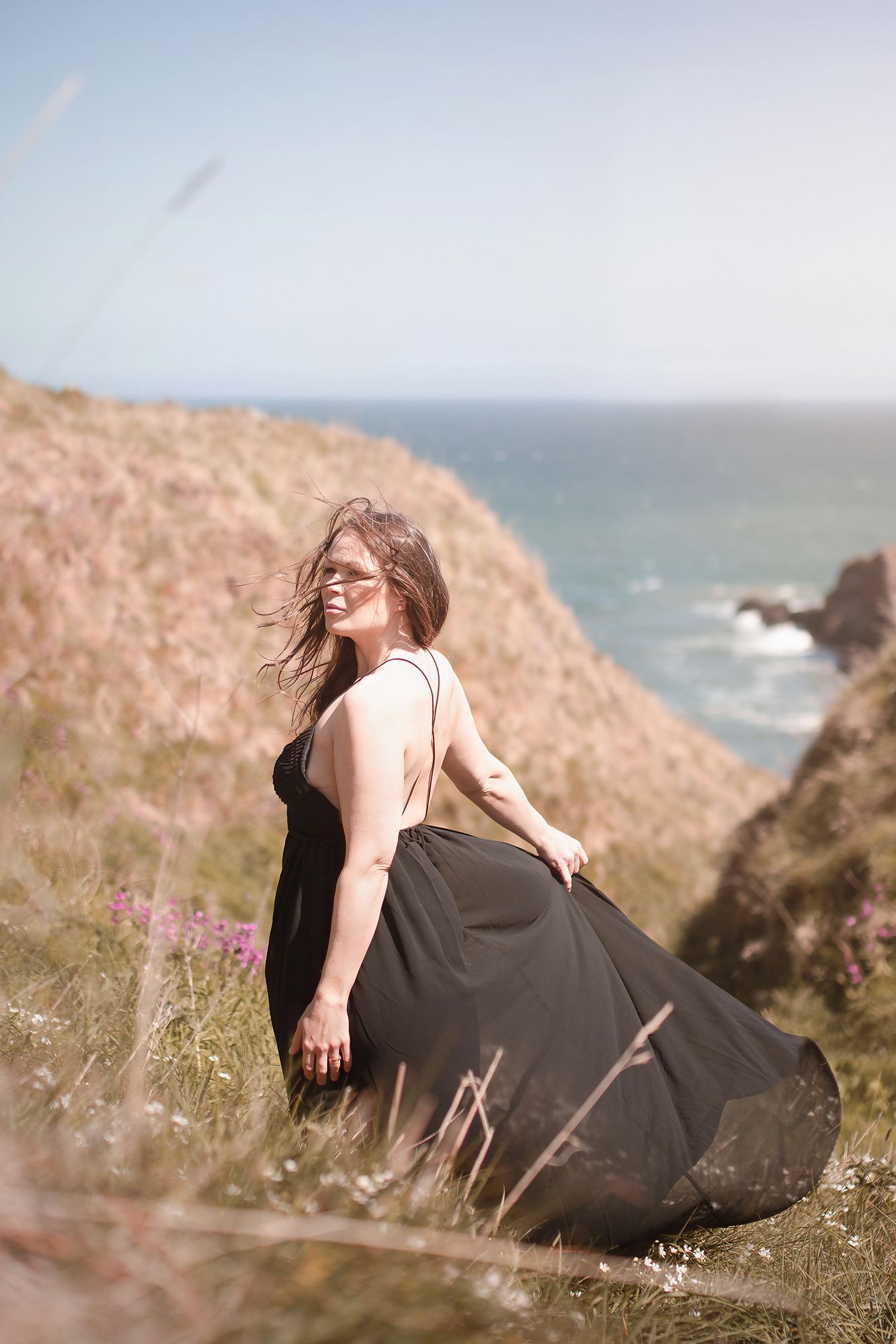 Vacker kvinna fotograferad vid sagolika Dunnottar Castle, Scotland i mjukt naturligt ljus.