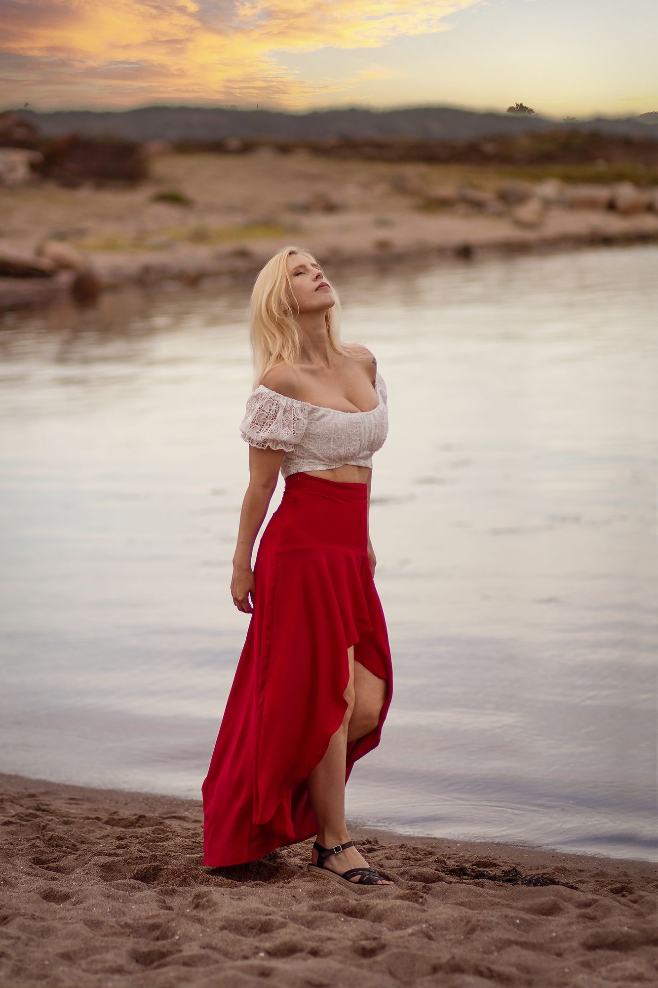 Drömlik foto på en blond kvinna i röd kjol vid strandkanten på Sveriges västkust, Lysekil utanför Göteborg.
