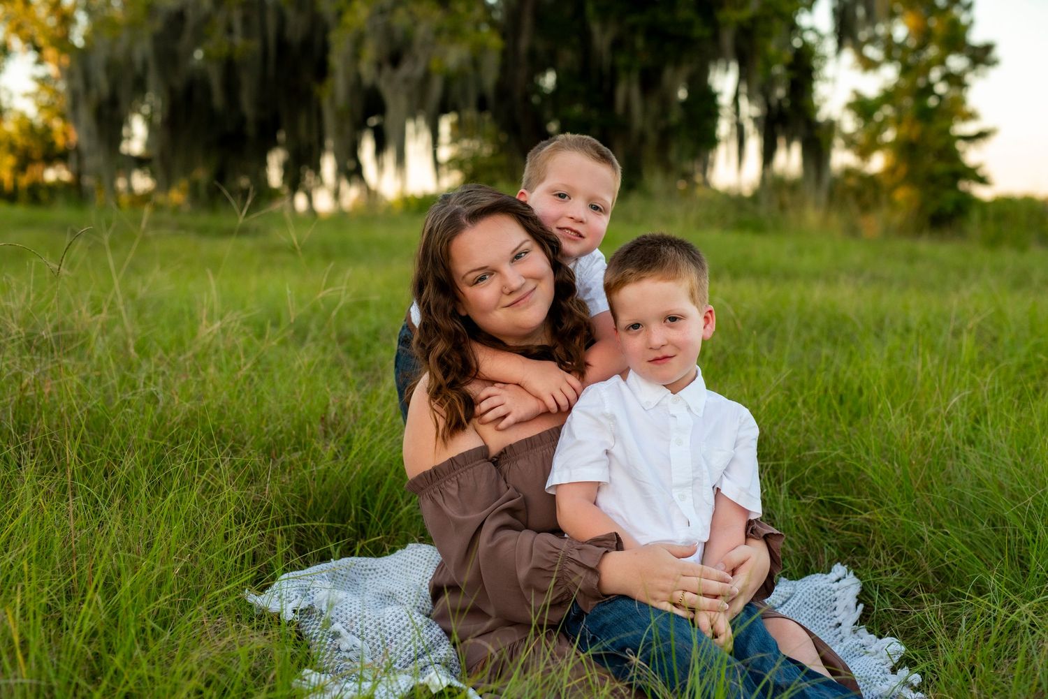 Mom posing with her two young boys at the Savannah Wildlife Refuge during an outdoor family photography session at golden hour.