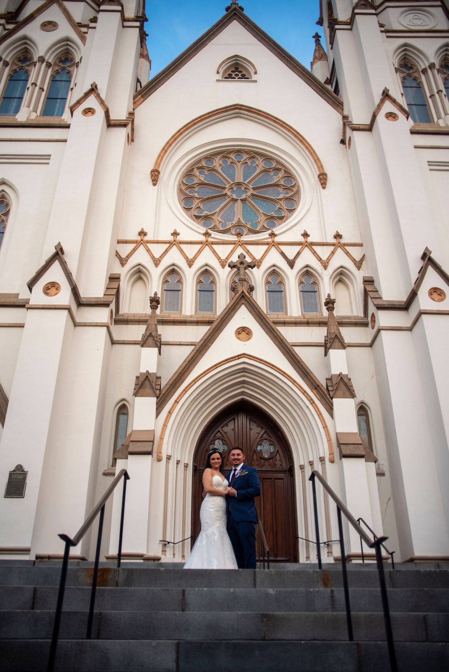 Newlywed couple standing together on the steps of St. John the Baptist Cathedral in Savannah.