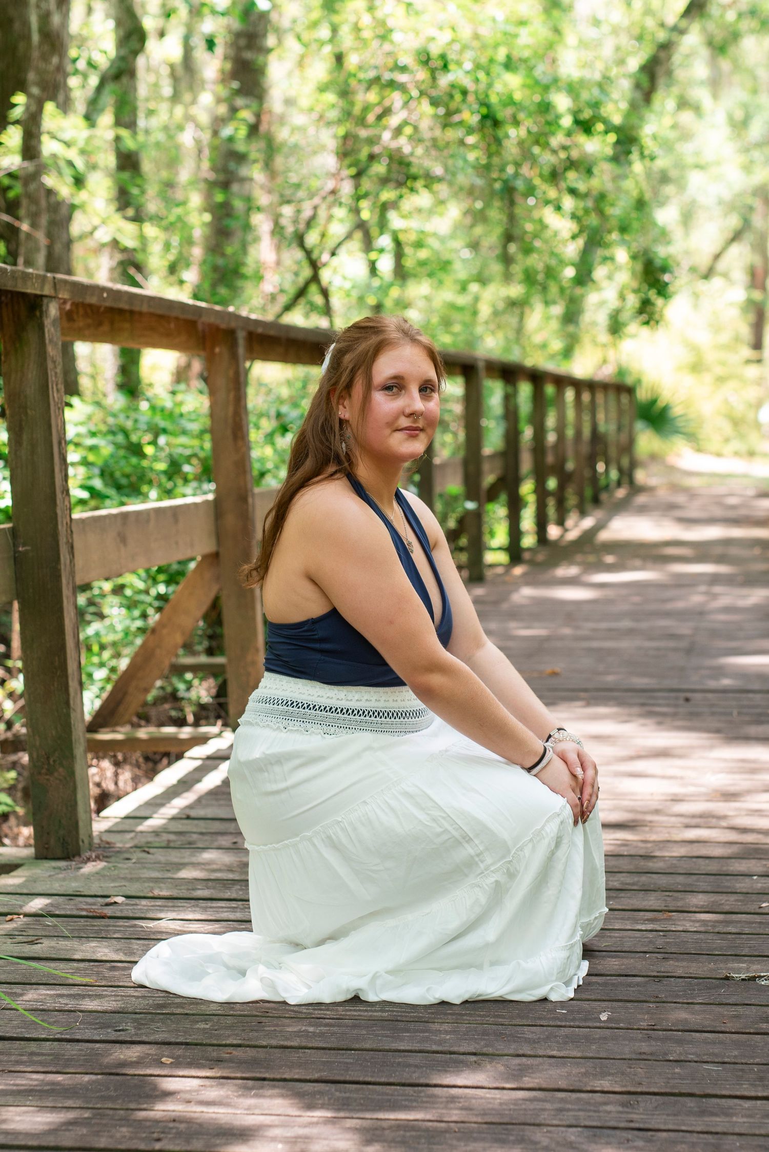 High school senior posing during an outdoor portrait session surrounded by lush greenery in a natural setting in Savannah, Georgia.