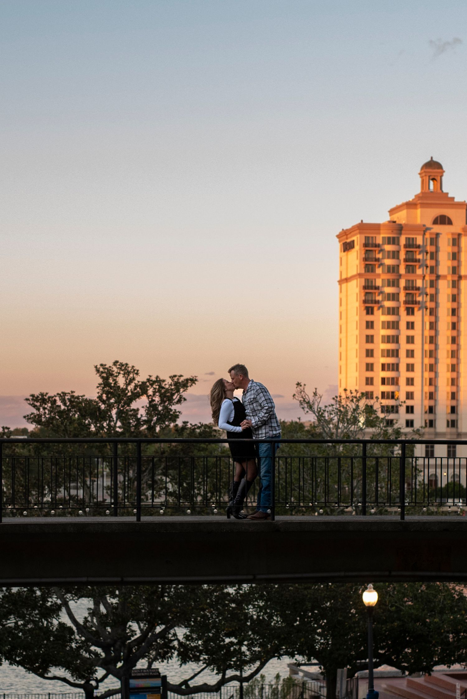 Couple kissing on a pedestrian bridge overlooking River Street in Savannah, Georgia, during a romantic couples photography session.
