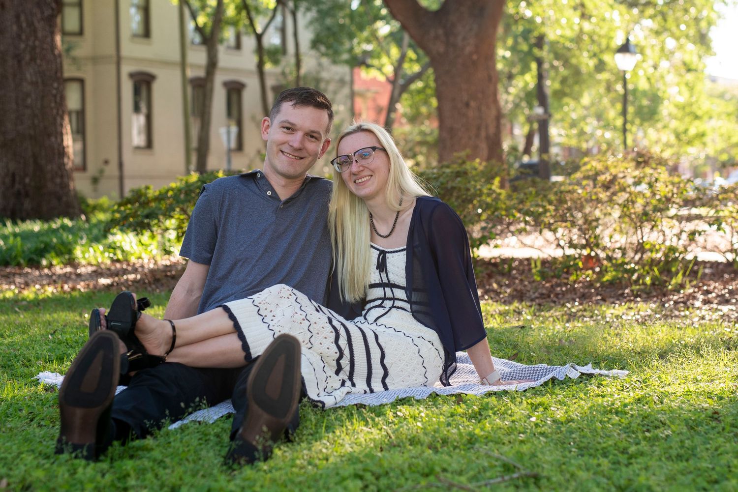 Couple sitting together on the ground at Whitfield Square in Savannah, Georgia, during a romantic outdoor couples photography session.
