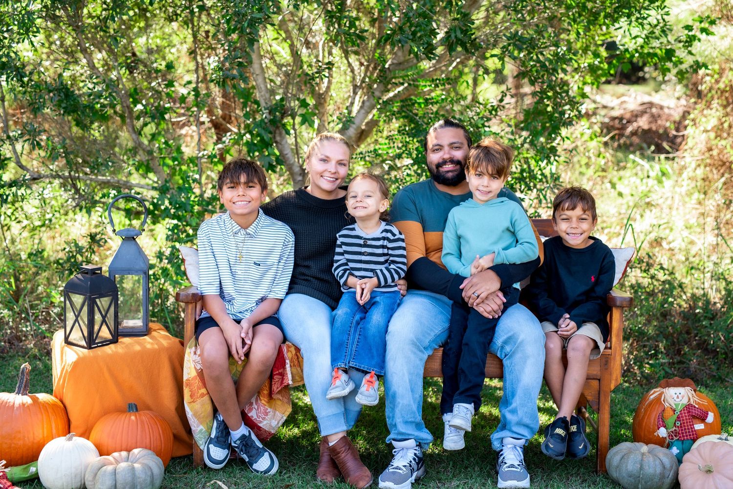 Family portrait of parents and their children posing together in a natural outdoor setting during a family photography session.