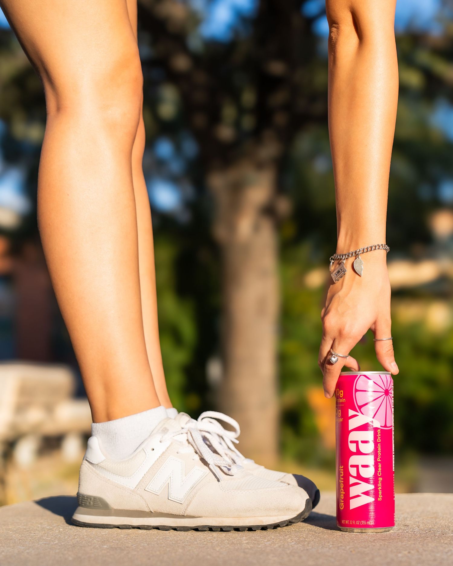 Side profile of female model outdoors in San Antonio, bending down to pick up a canned drink during a branded photoshoot.
