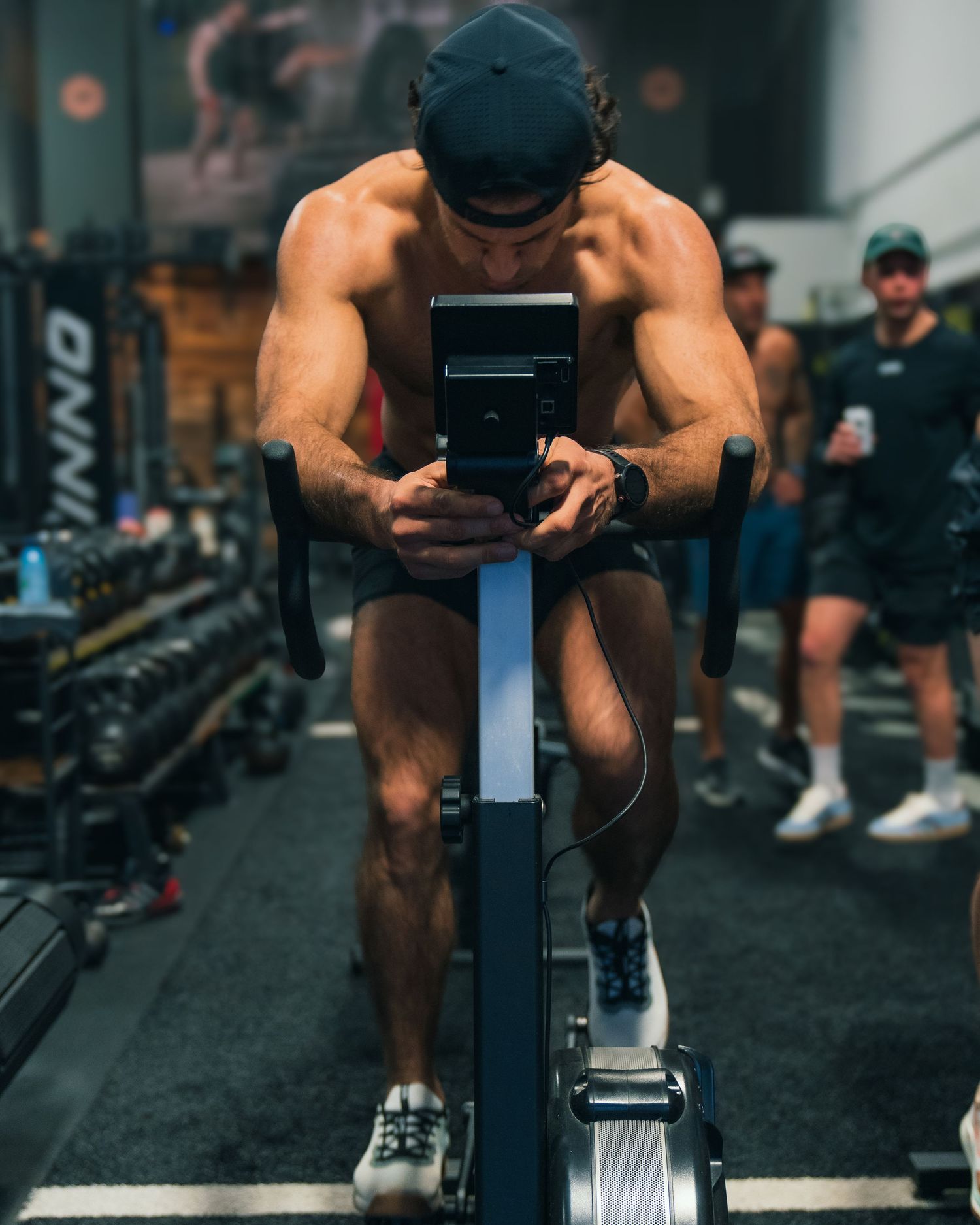 Male fitness influencer photoshoot by TenX Captures working out on stationary bike facing forward in Austin gym for social media content.