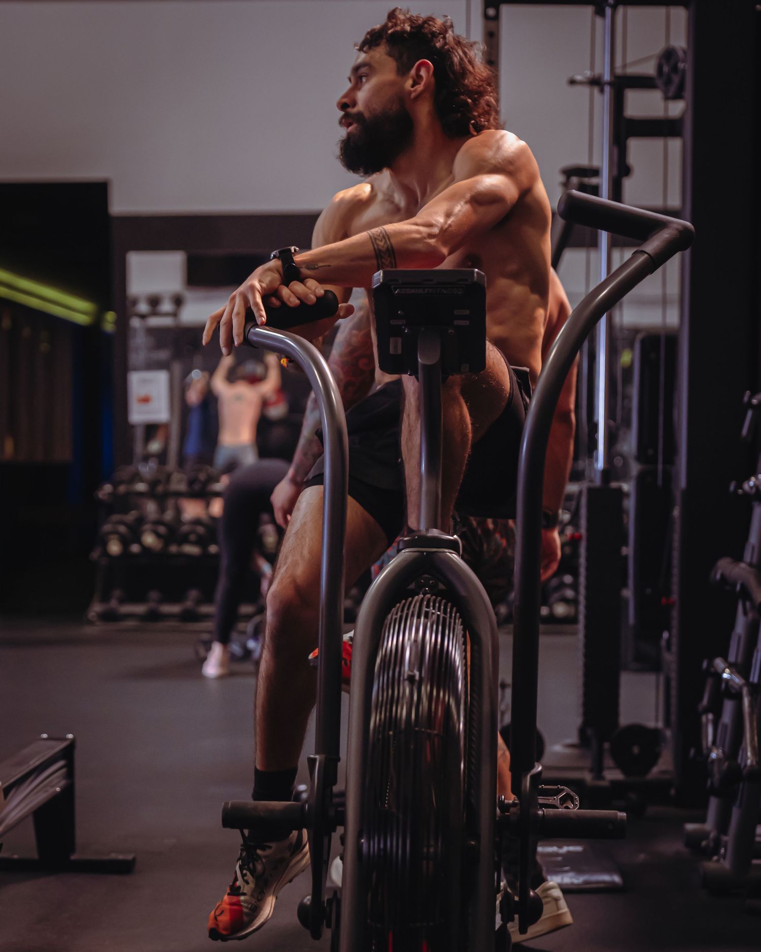 Fitness influencer photoshoot by TenC Captures sitting on stationary bike looking away in Austin gym for social media content.