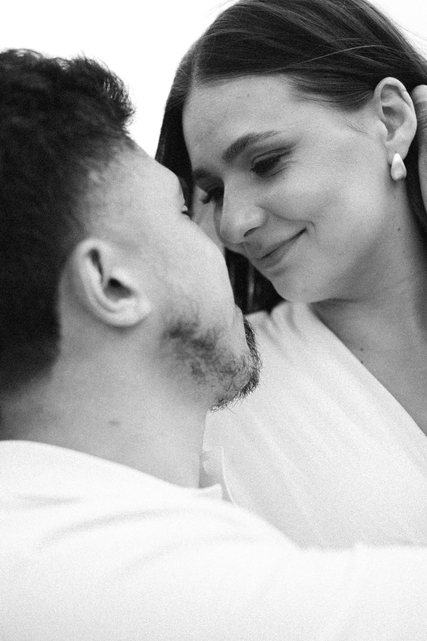 Black and white romantic couple portrait, woman smiling tenderly at man in intimate close-up pose.