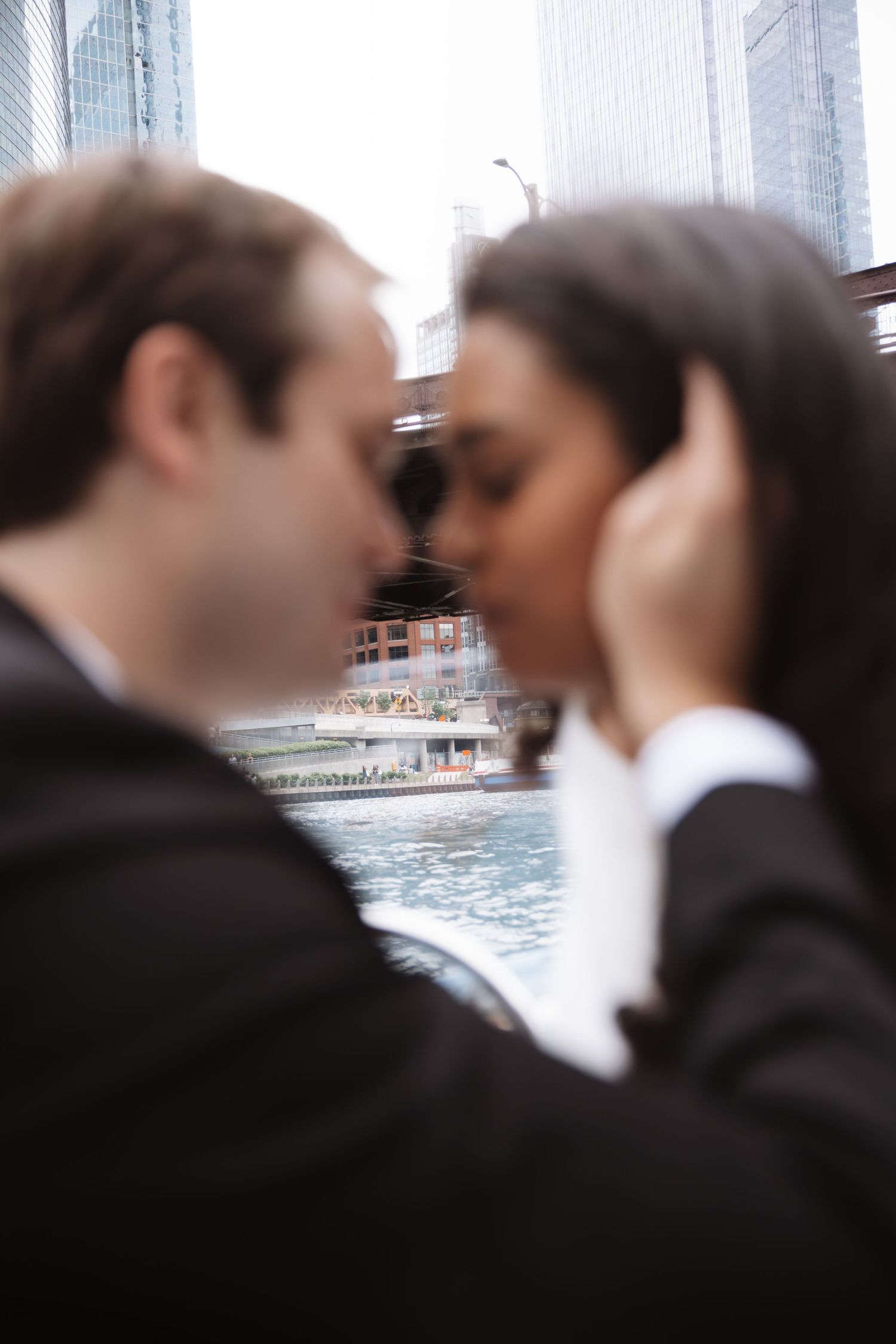Couple about to kiss on a boat with Chicago River and skyscrapers in background.
