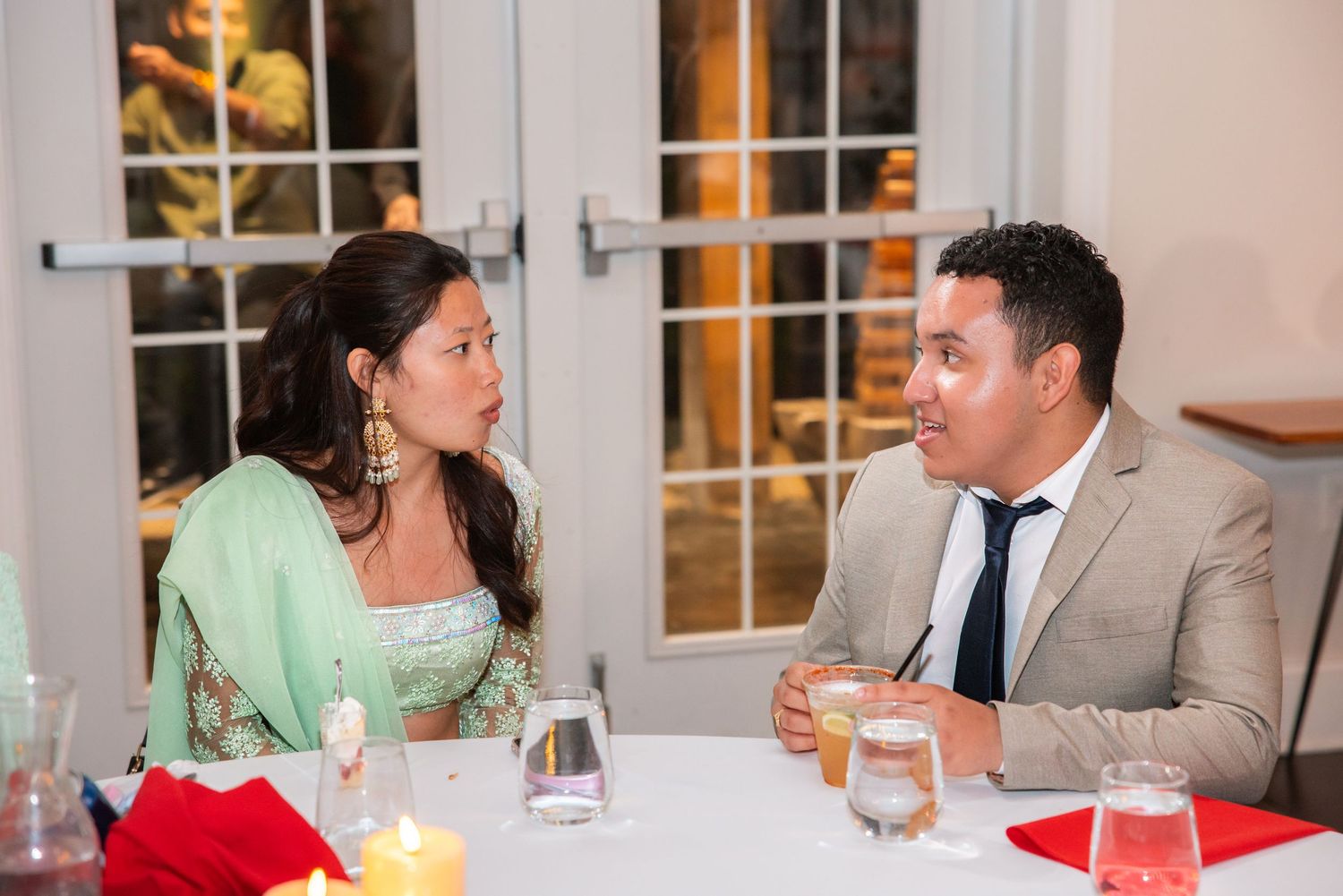 Man and woman in formal attire having conversation at decorated wedding reception table.