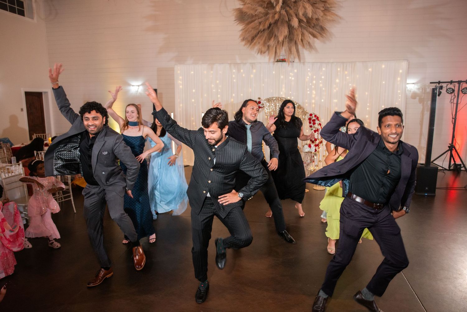 Men performing an energetic choreographed dance at an Indian wedding reception.