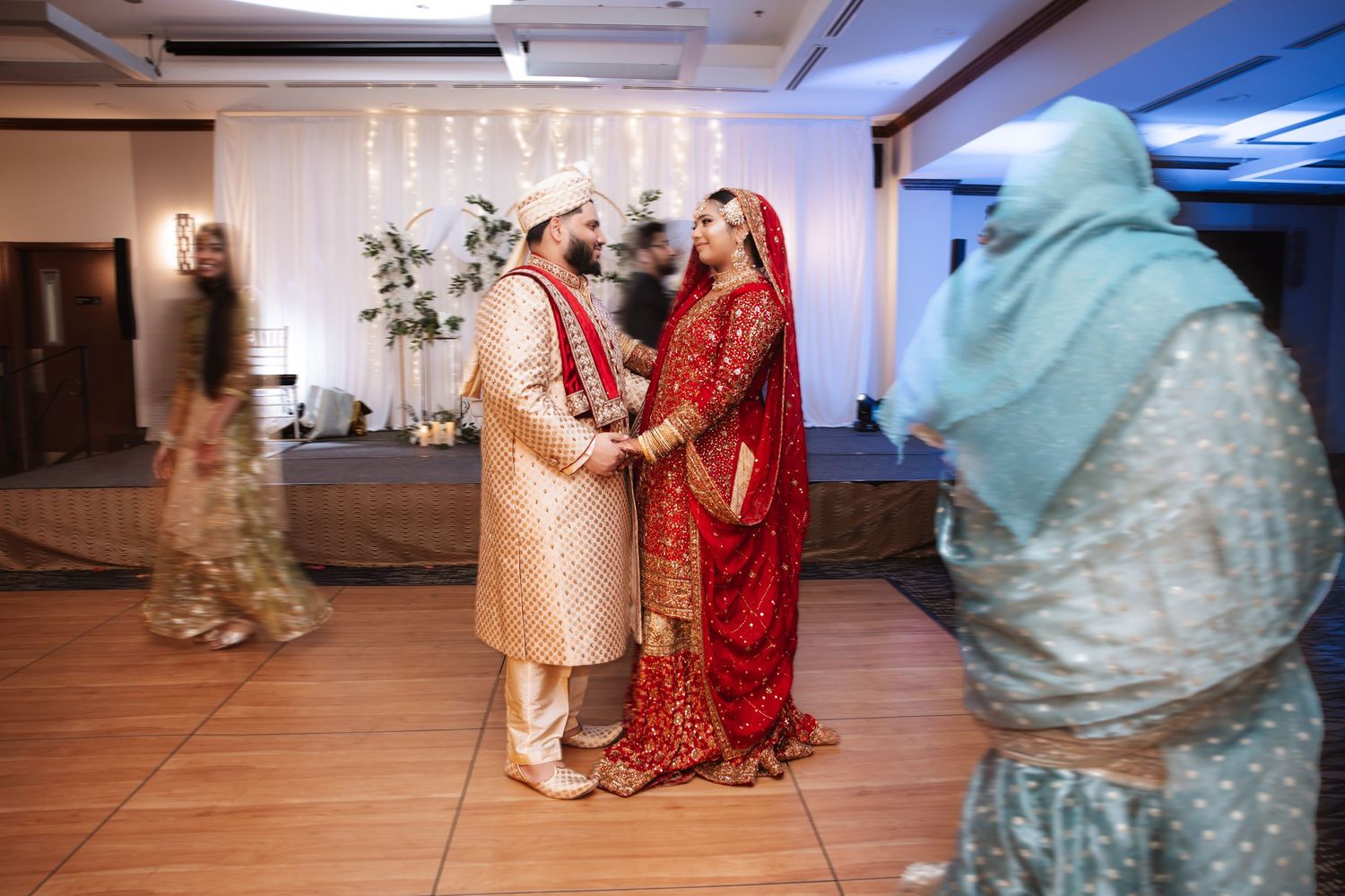 South Asian bride and groom in traditional red and gold bridal wear during wedding ceremony.