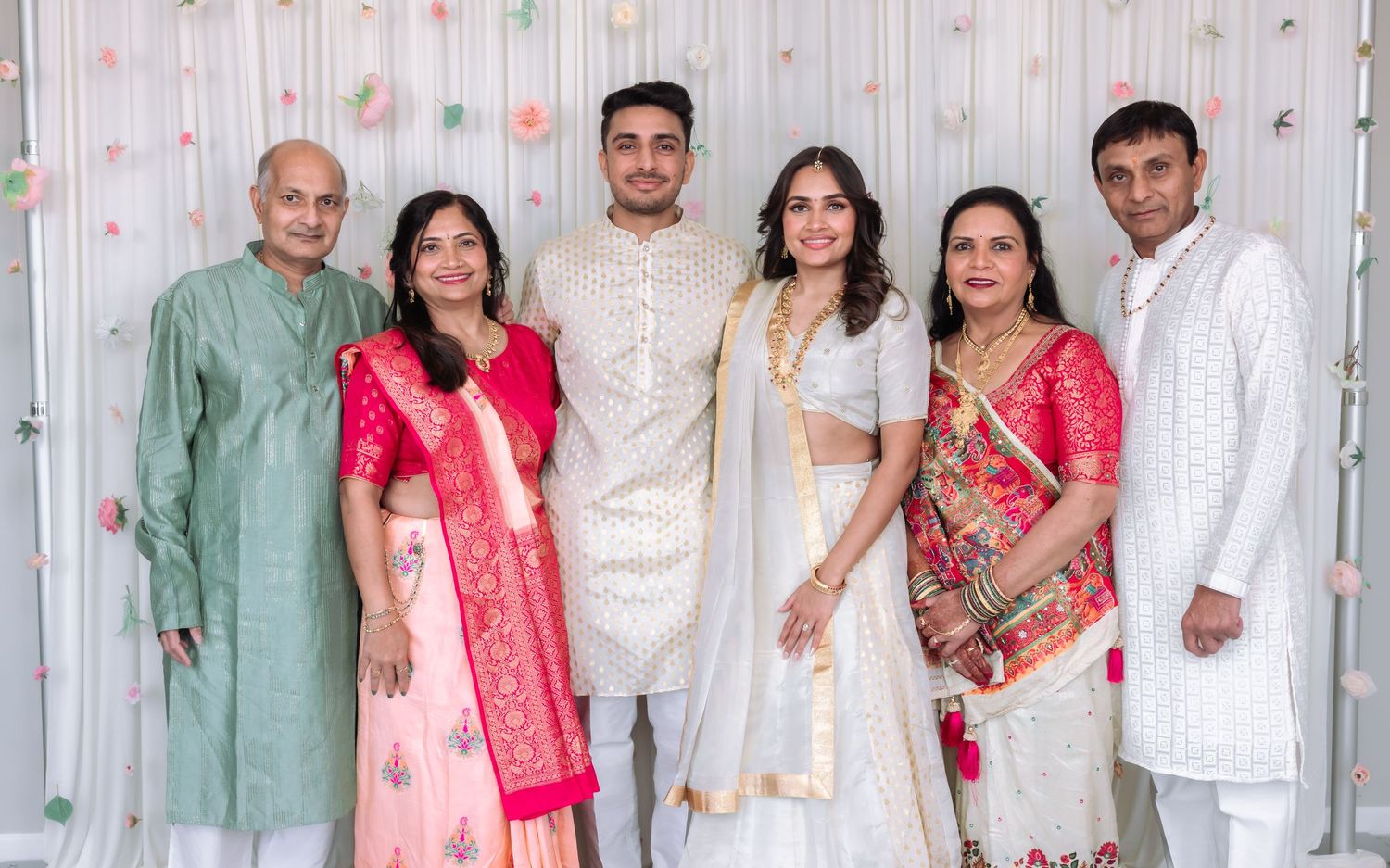 Indian family of six posing together in colorful traditional attire at a wedding celebration.