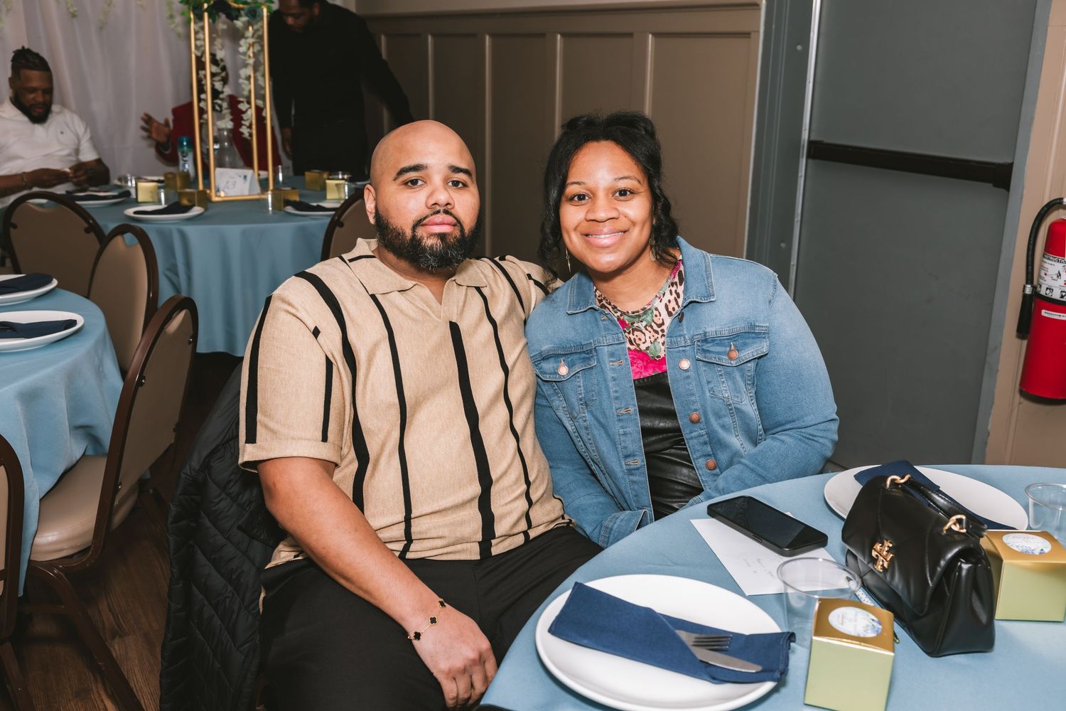 Couple smiling together at a wedding reception dinner table.