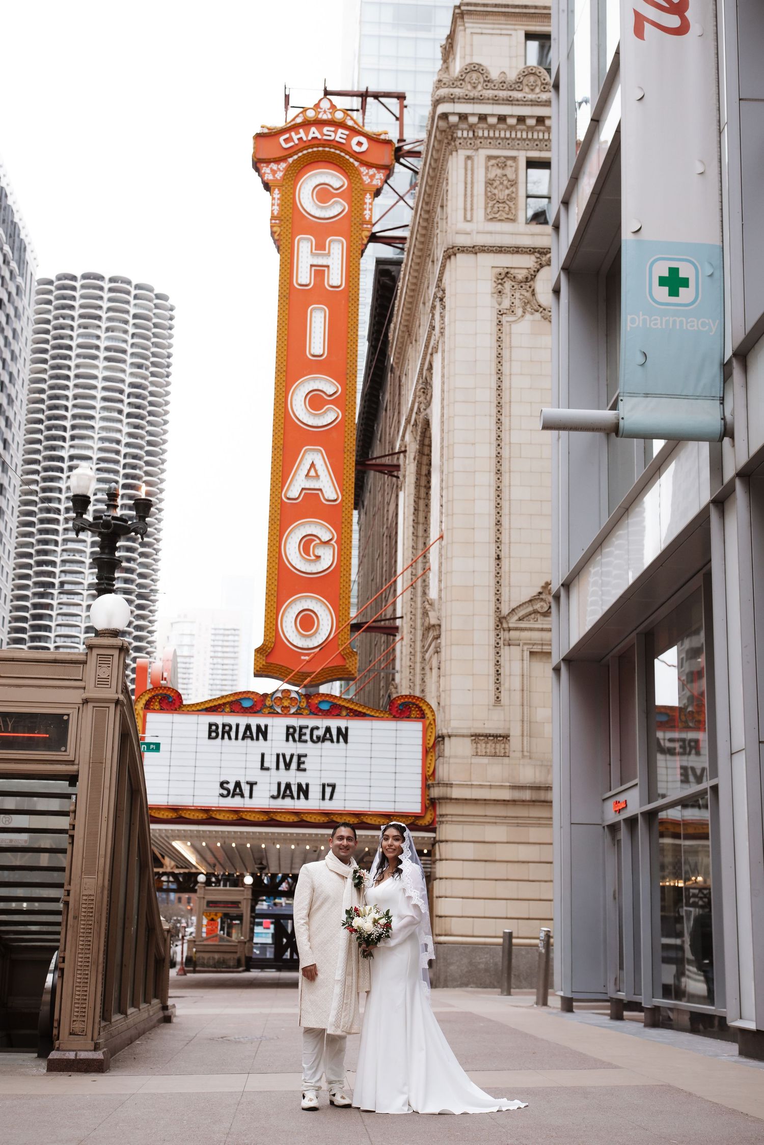 Couple in wedding attire standing beneath the Chicago Theatre marquee on January 17th.