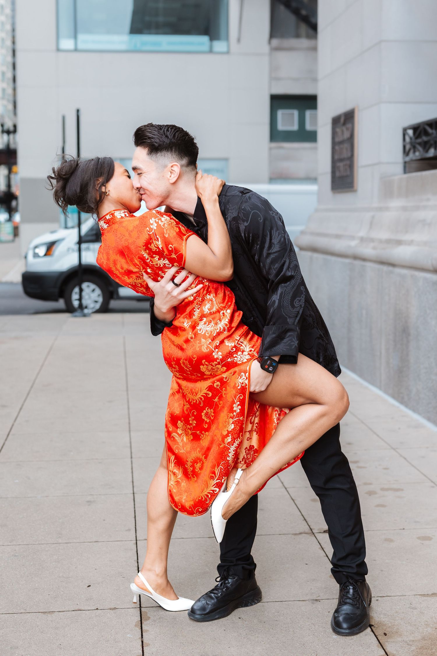 Couple in traditional Chinese attire sharing a romantic dip kiss on a Chicago city sidewalk.

Chicago Wedding Photographer