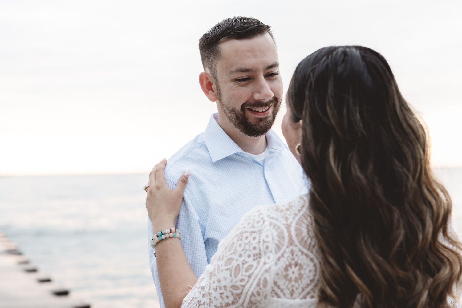Happy couple embracing and smiling at each other during a lakeside engagement photo session.